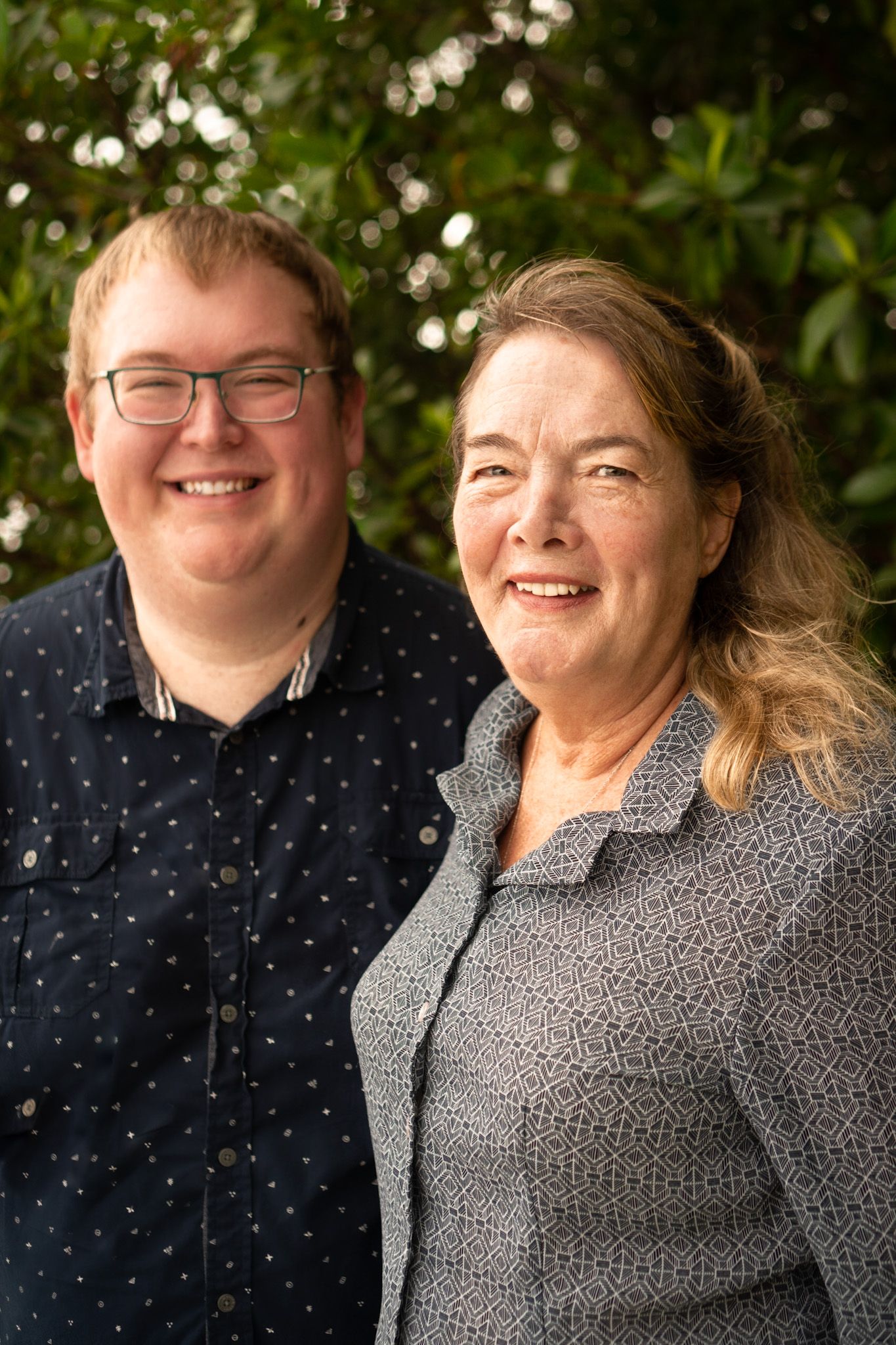 Two people in casual attire smile together during an outdoor photo session.