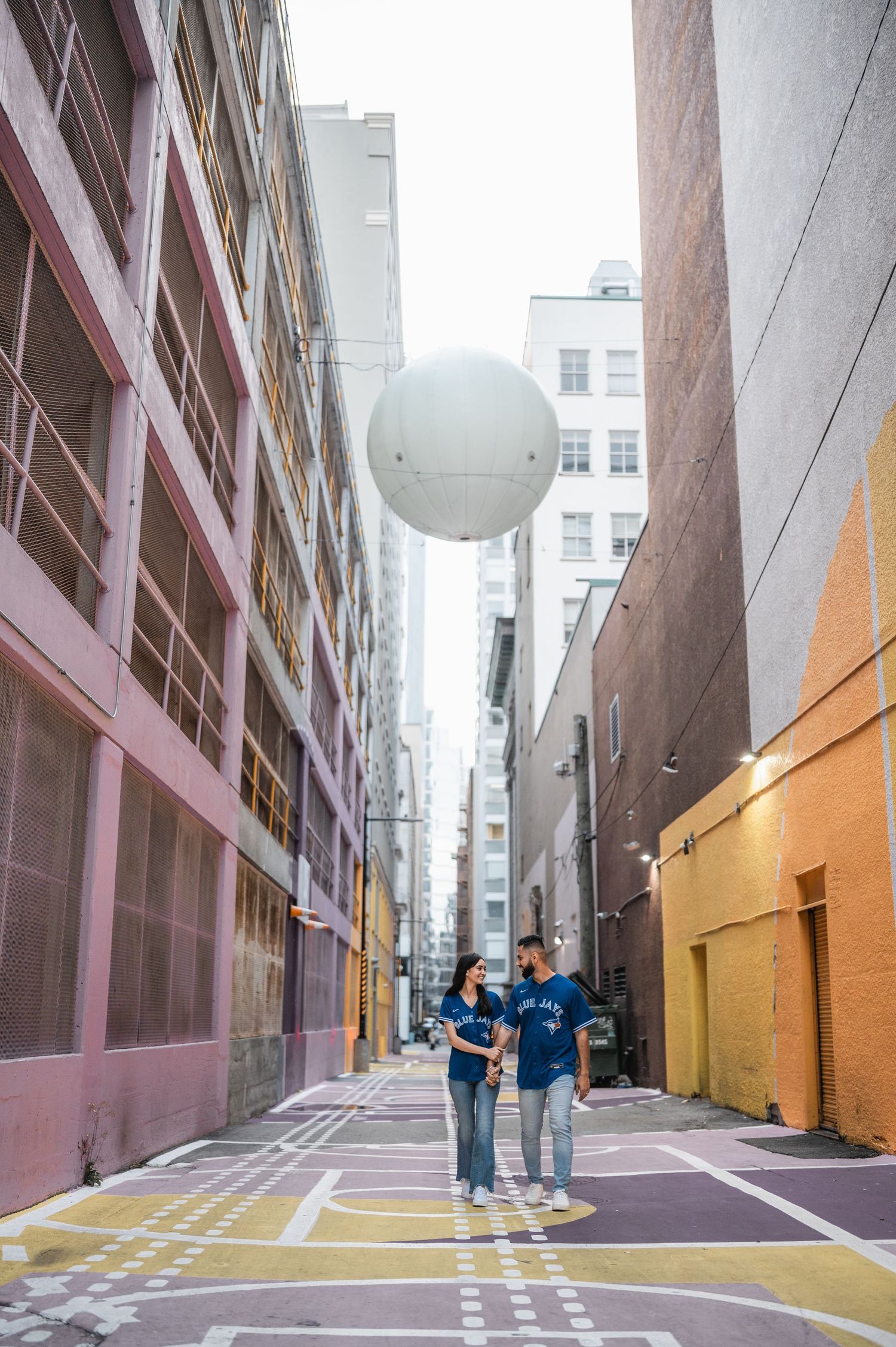 White balloons floating in vibrant urban alley with geometric patterns.
