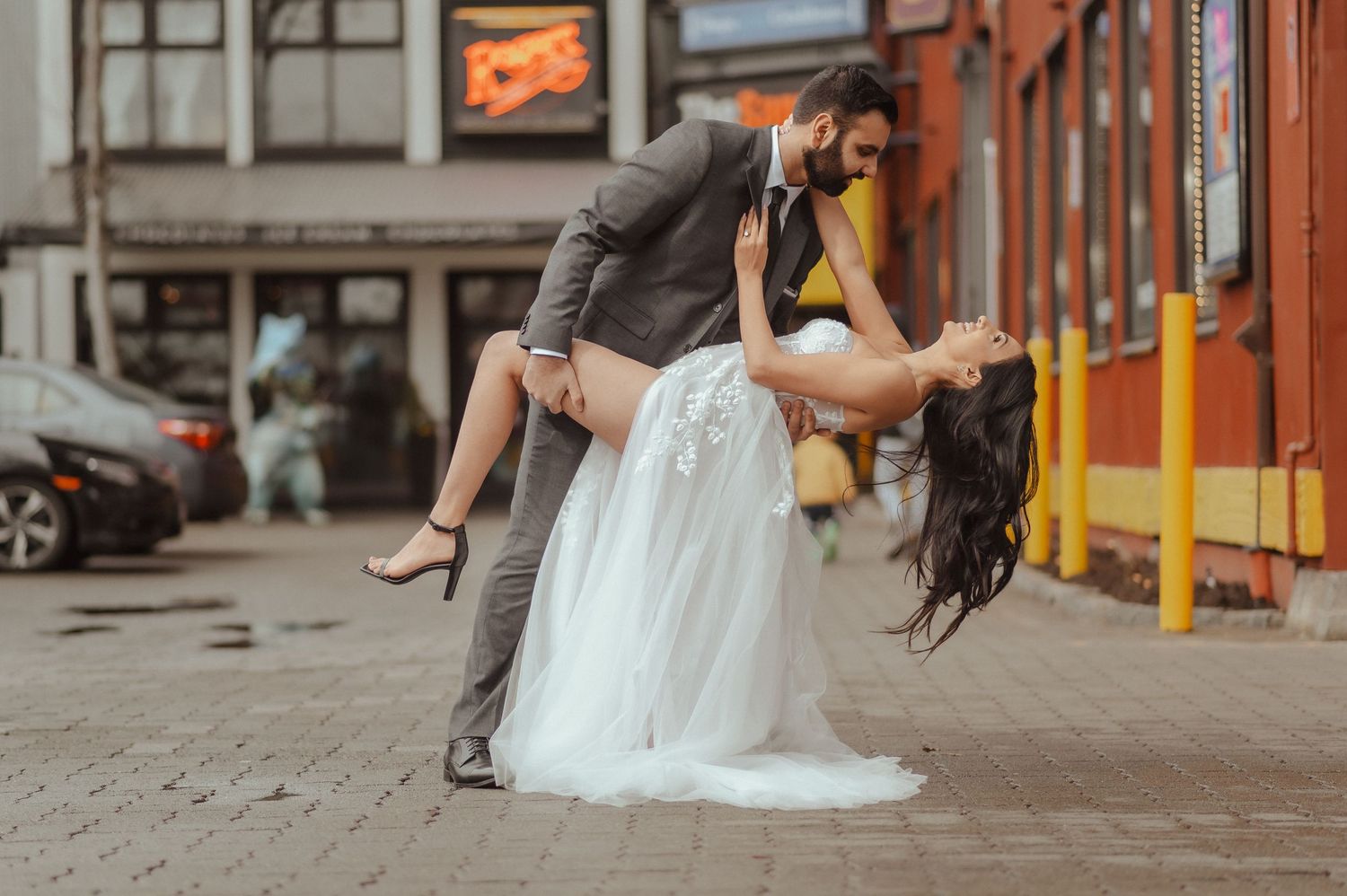 A romantic urban photoshoot with brick buildings and storefronts in the background.