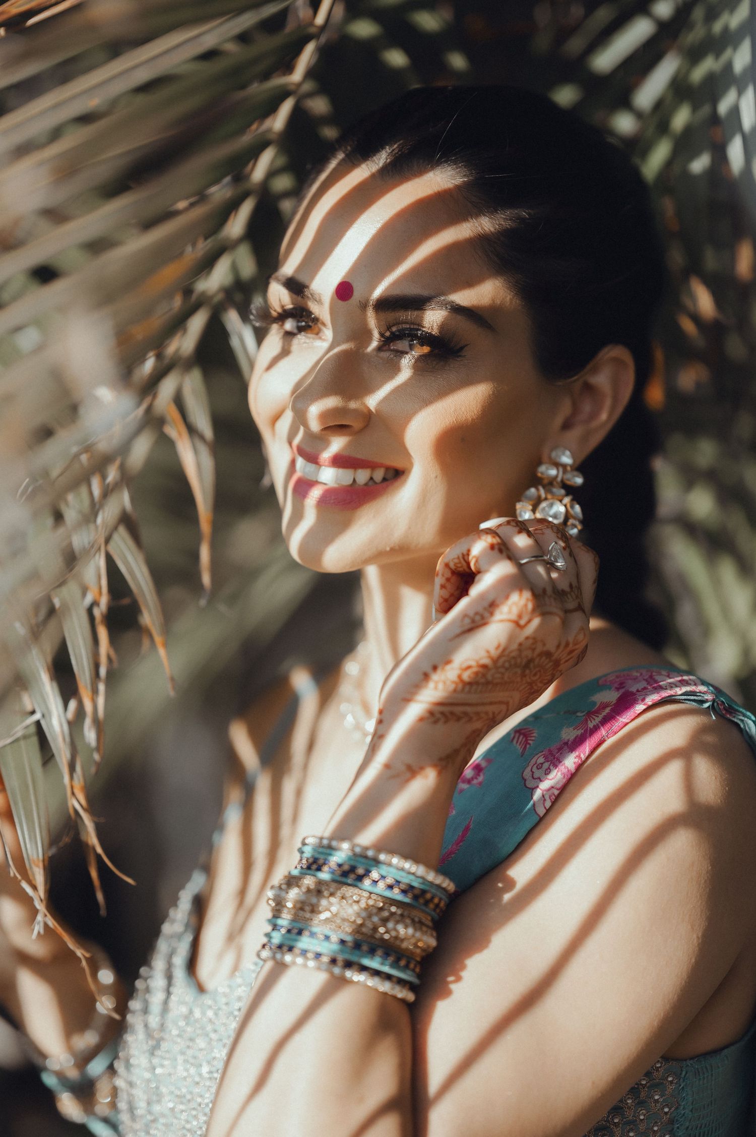 Close up detail shot of bridal jewelry and bangles with soft sunlit effect through leaves creating a warm artistic portrait.