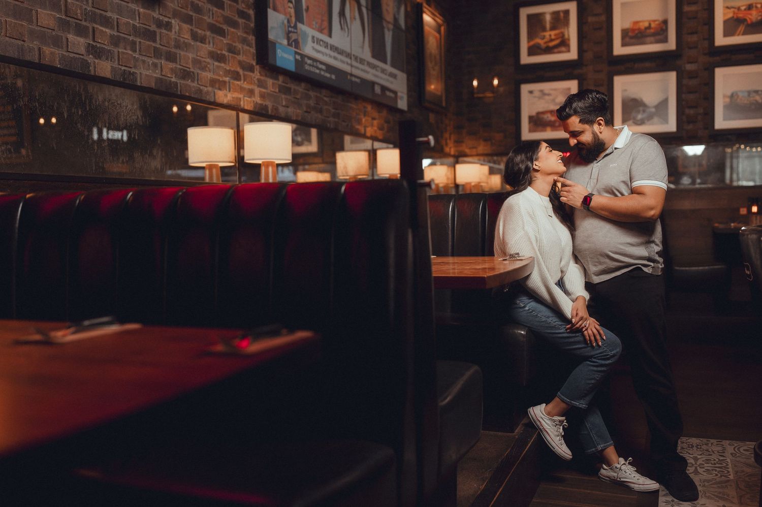 Couple enjoying conversation in casual restaurant with brick walls and booth seating.