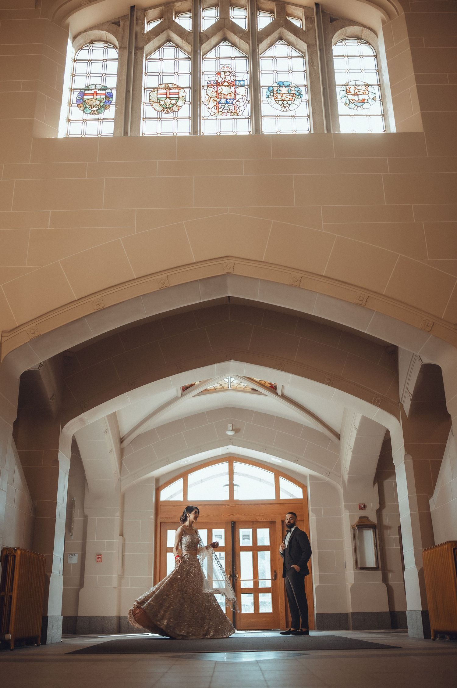 A romantic scene in a Gothic-style corridor with arched ceilings and stained glass windows illuminating the elegant space.