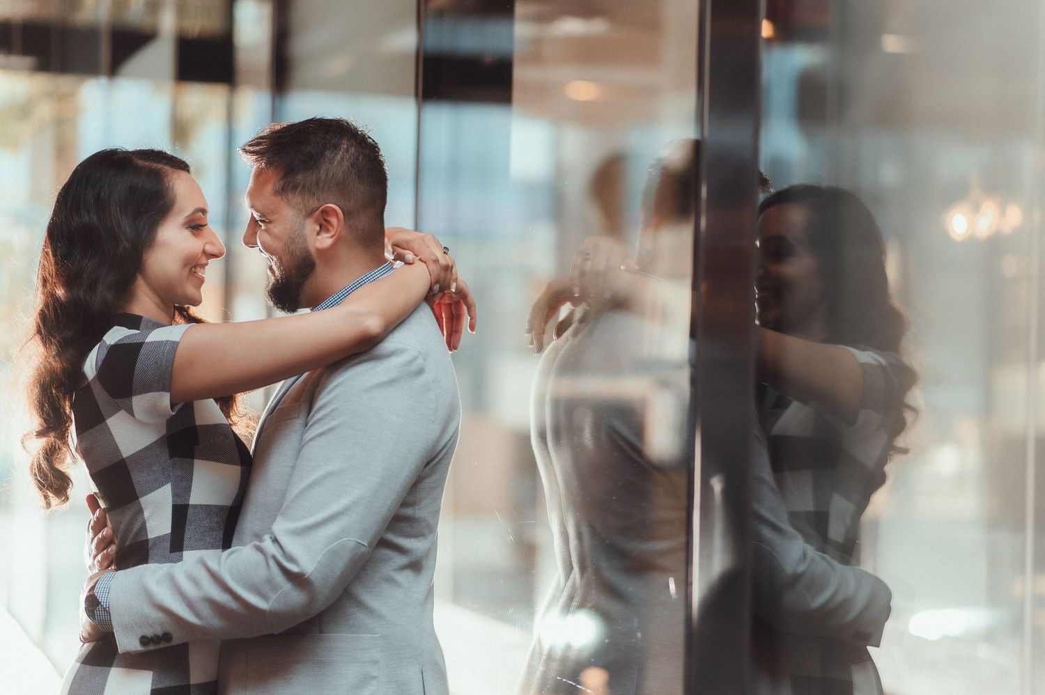 Romantic silhouettes of a couple embracing against window reflections.