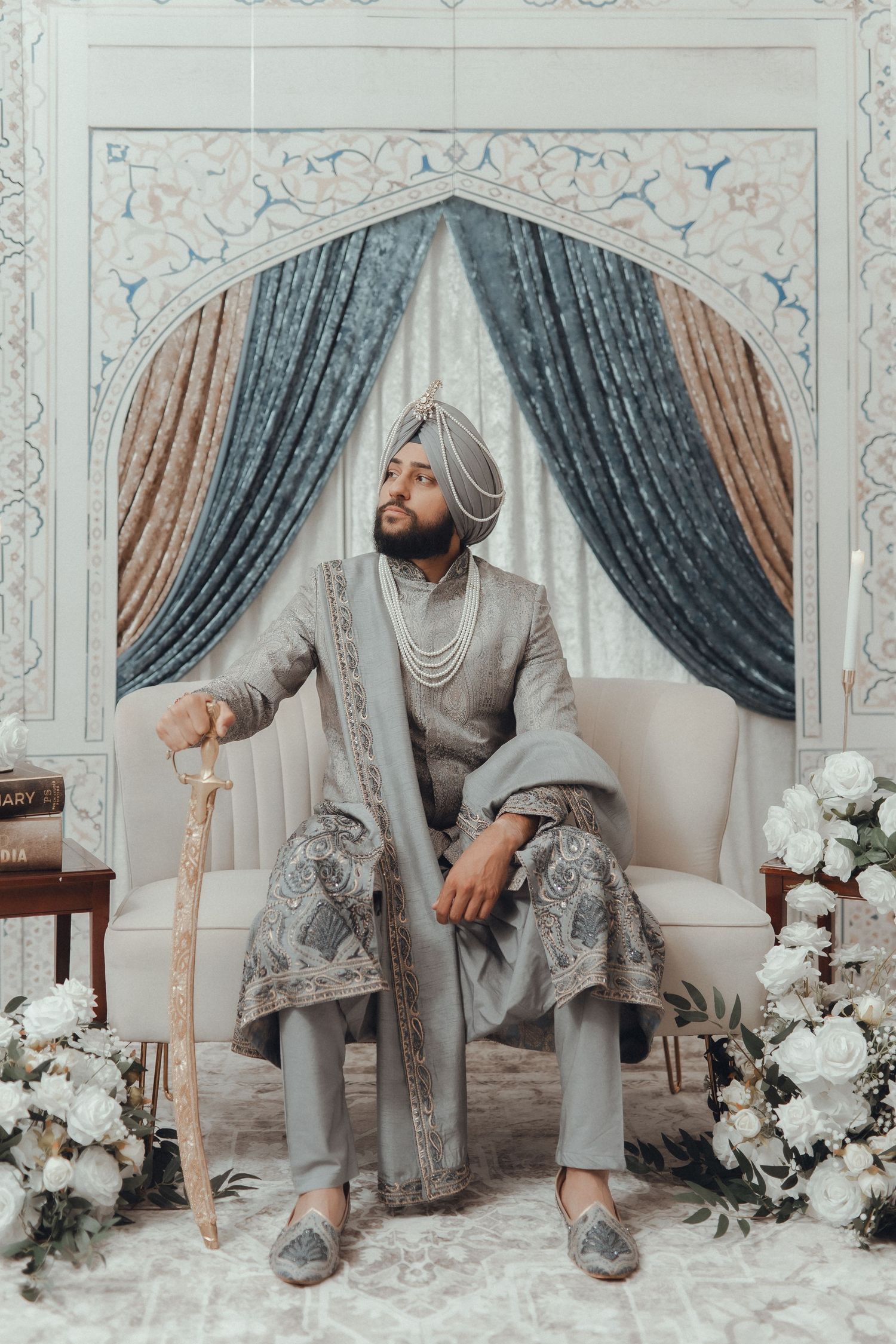 Elegant wedding setup with ornate white and grey decor featuring floral arrangements.