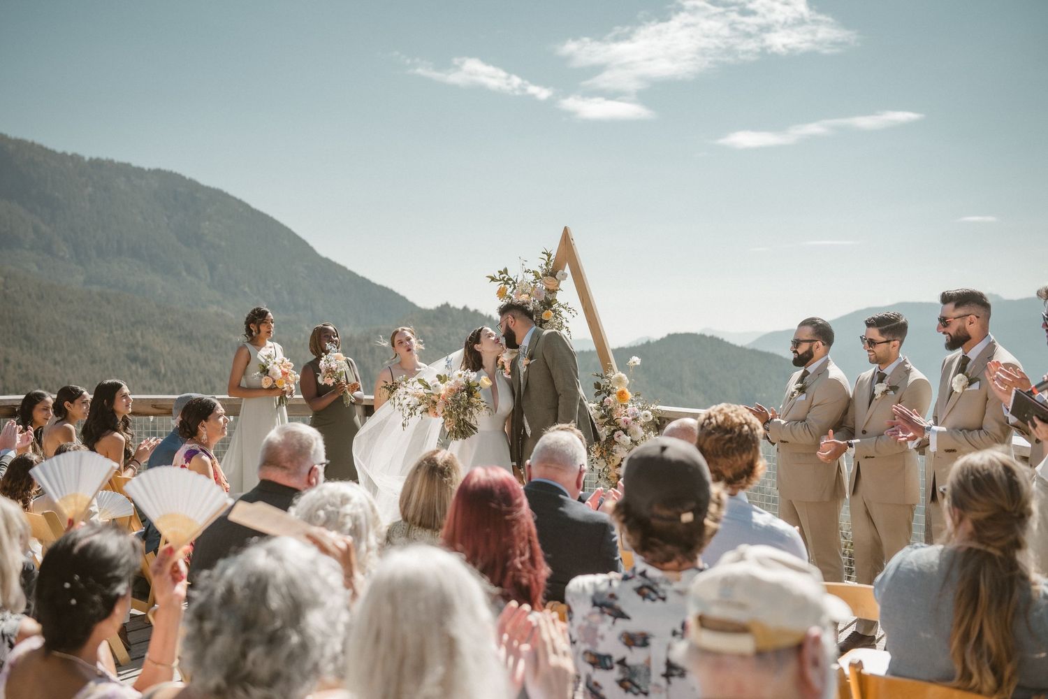 Outdoor wedding celebration with guests gathered in front of mountain landscape.