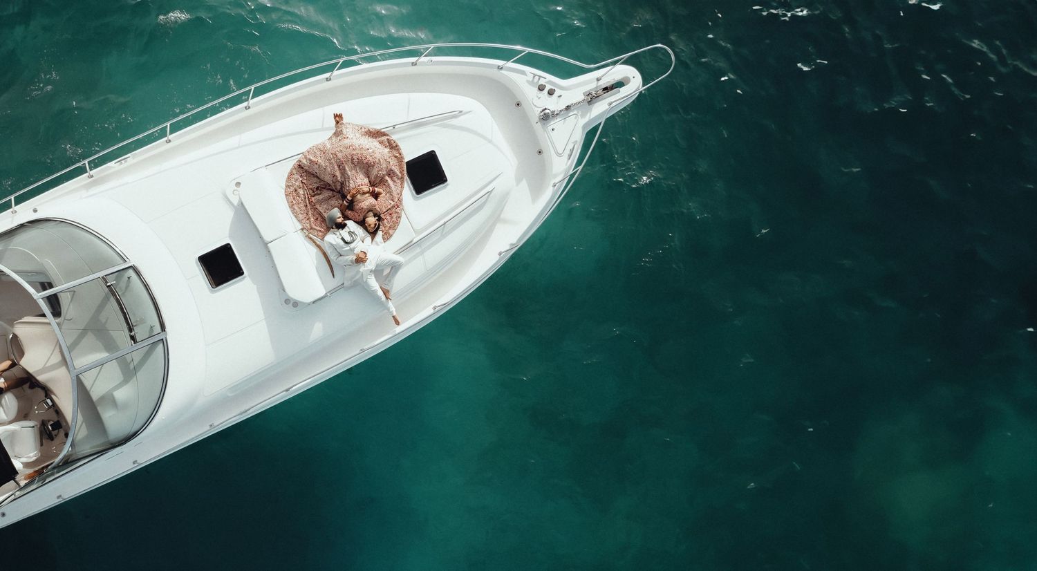 Aerial view of boats and small watercraft anchored in turquoise waters near a white sandy beach.