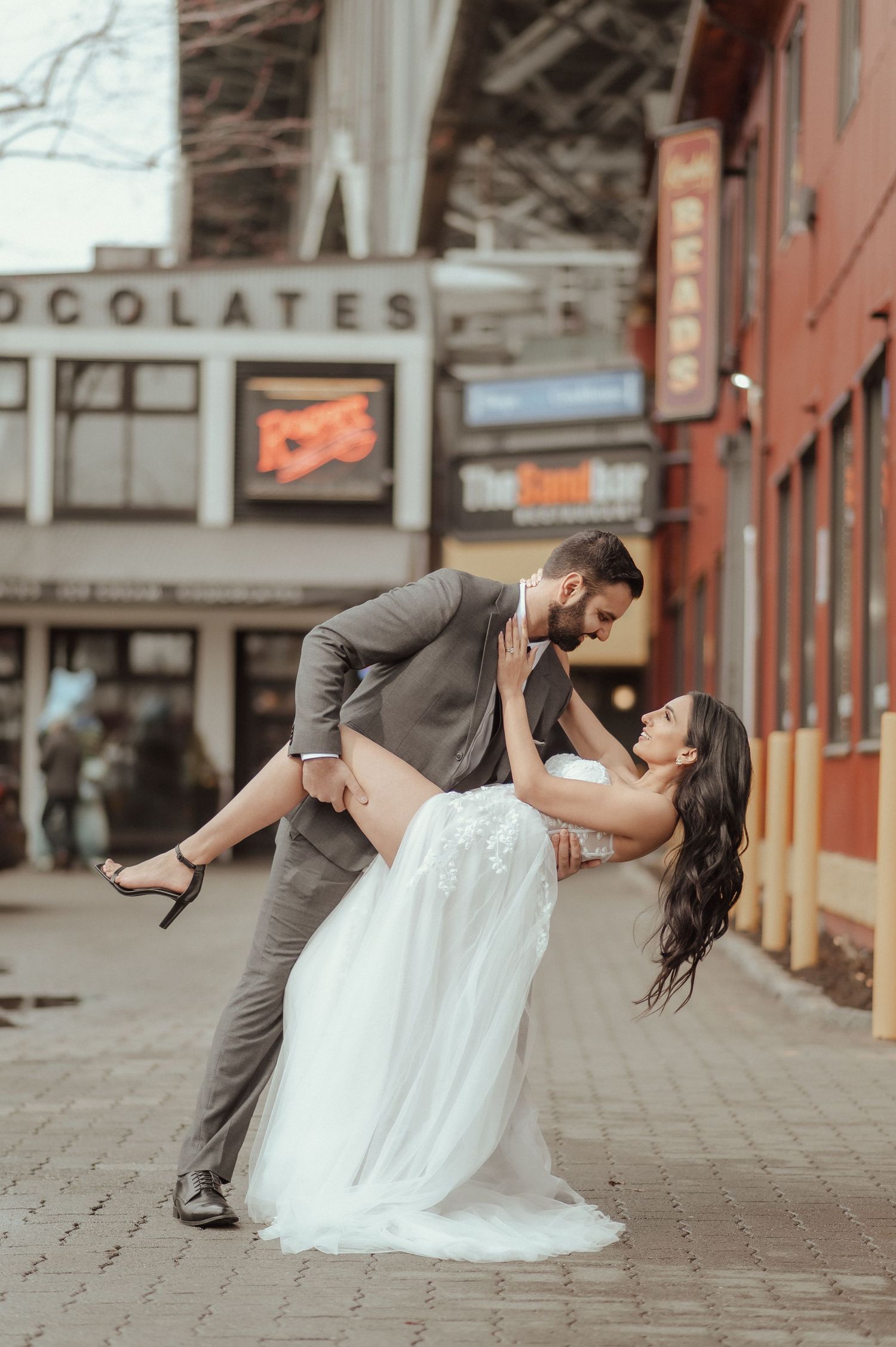 A romantic dip pose captured on cobblestone streets with brick buildings in the background.