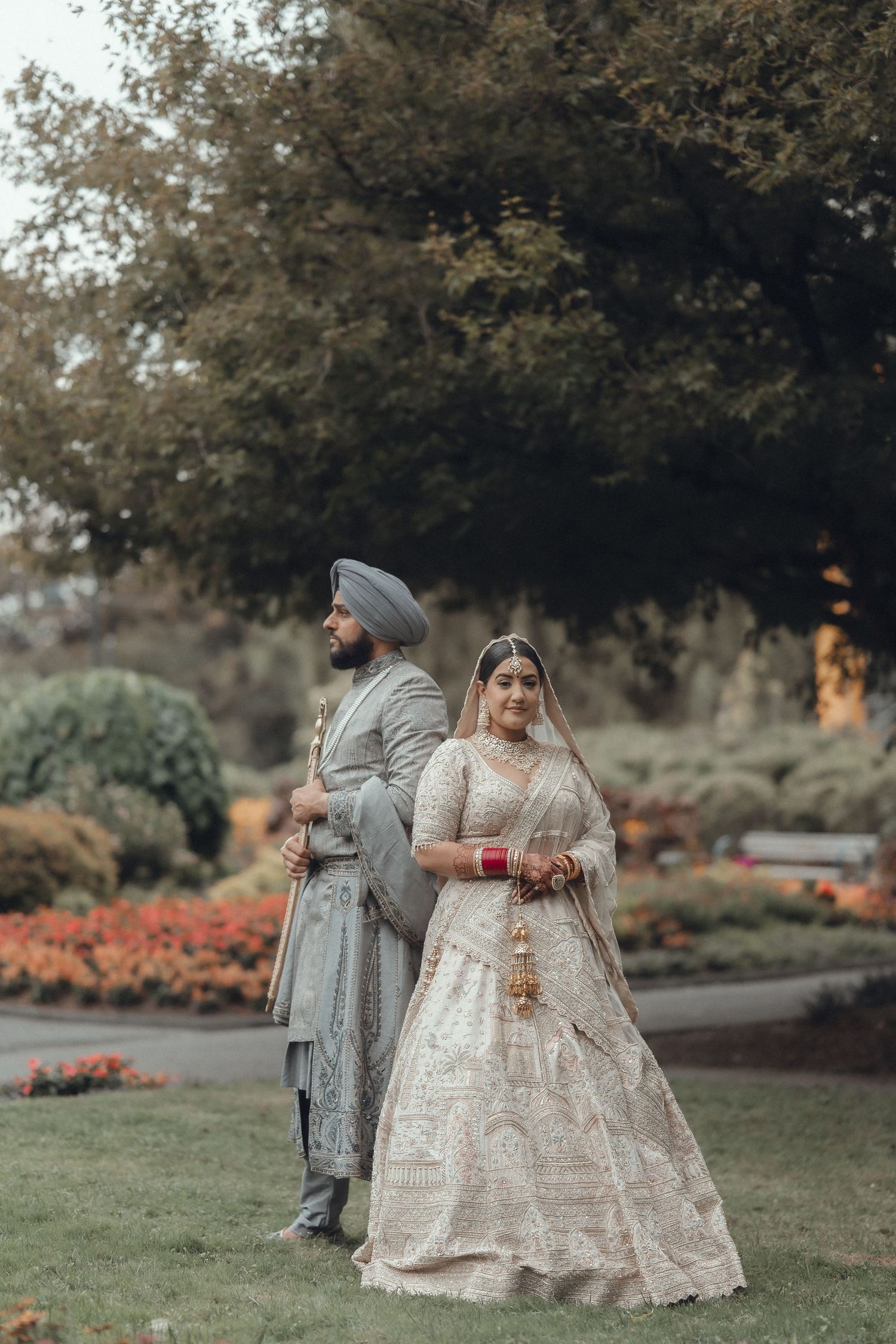 Couple in traditional Indian wedding attire walking together in a garden setting.