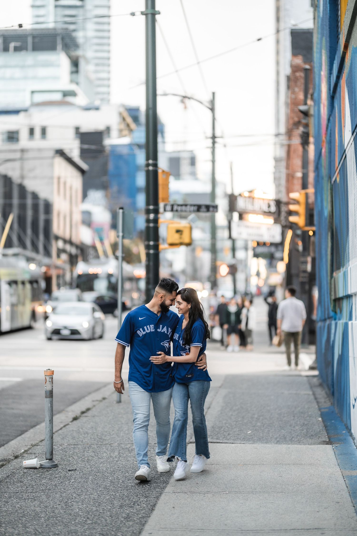 Couple wearing casual blue outfits walking together along an urban sidewalk.