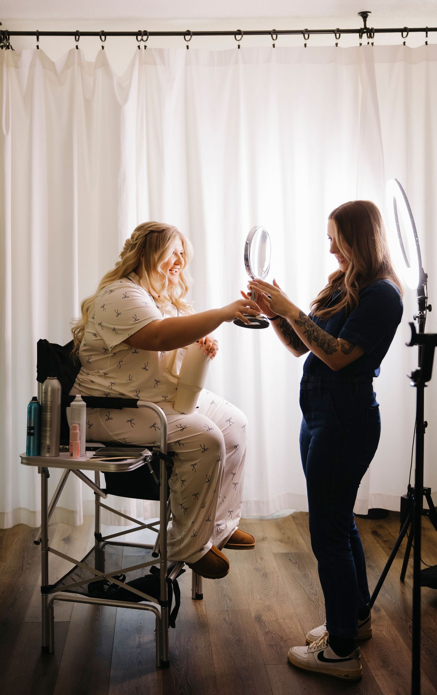Wedding preparation scene showing people getting ready in a bright room with white curtains.