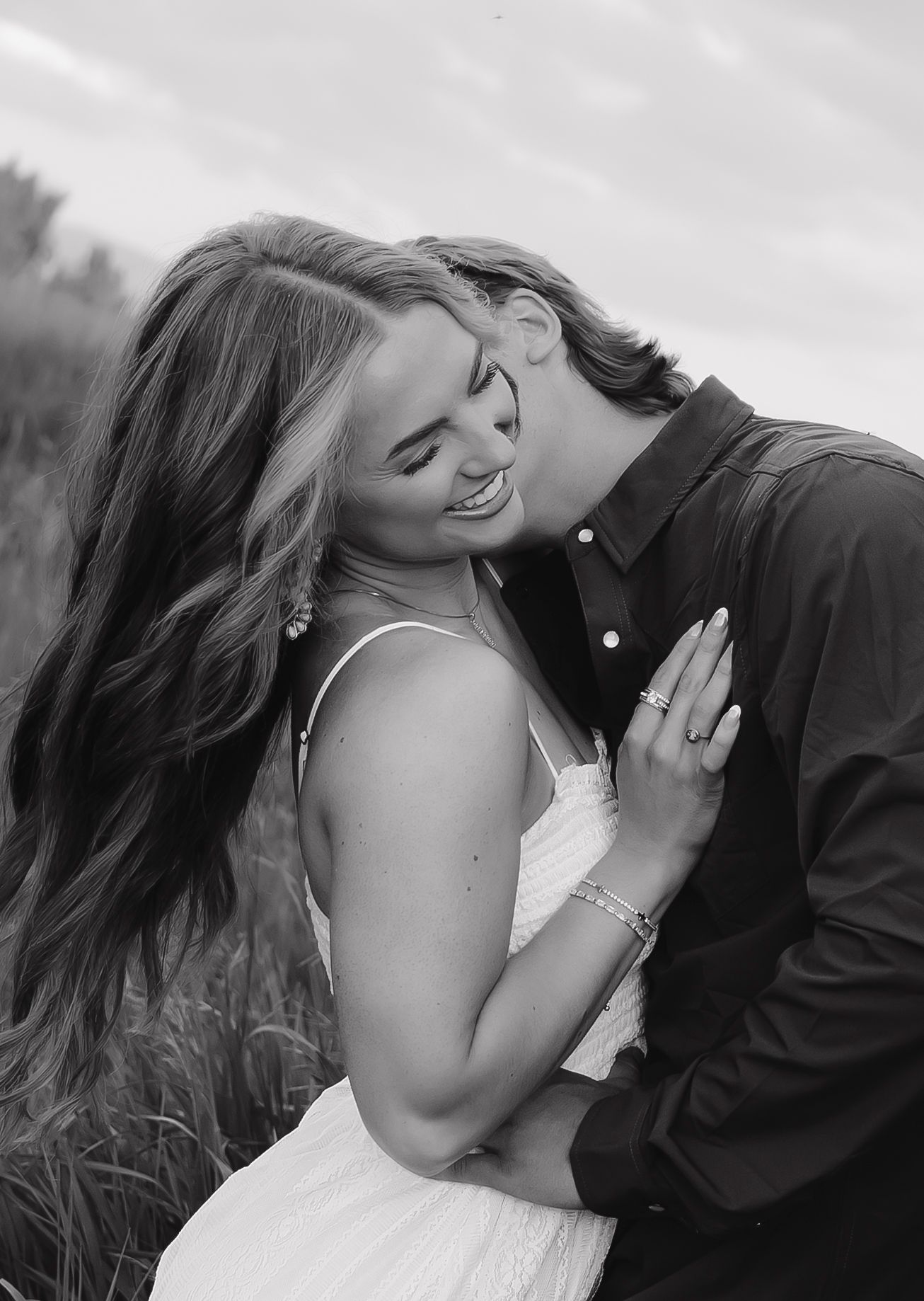 Black and white portrait of an intimate moment between a couple in a field.