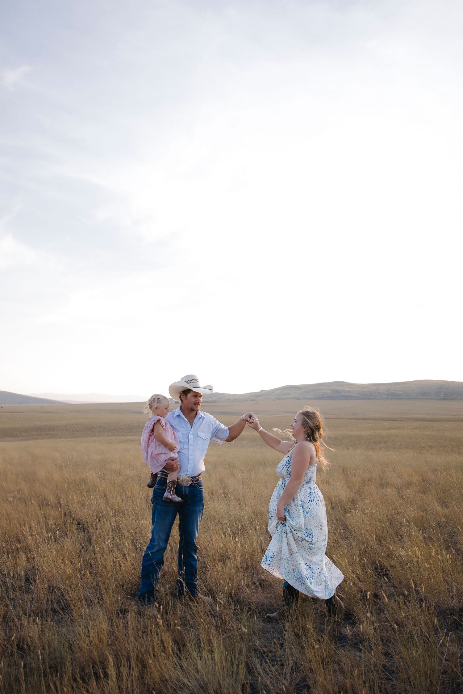 People dancing and playing in a golden grass field at dusk.