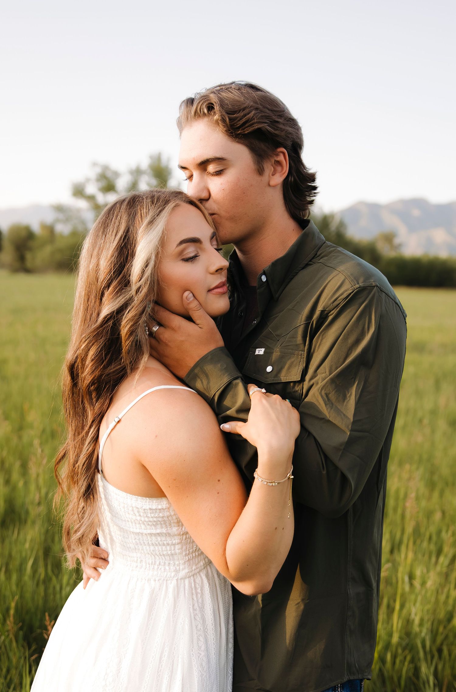A romantic moment between a couple in a green field during golden hour.