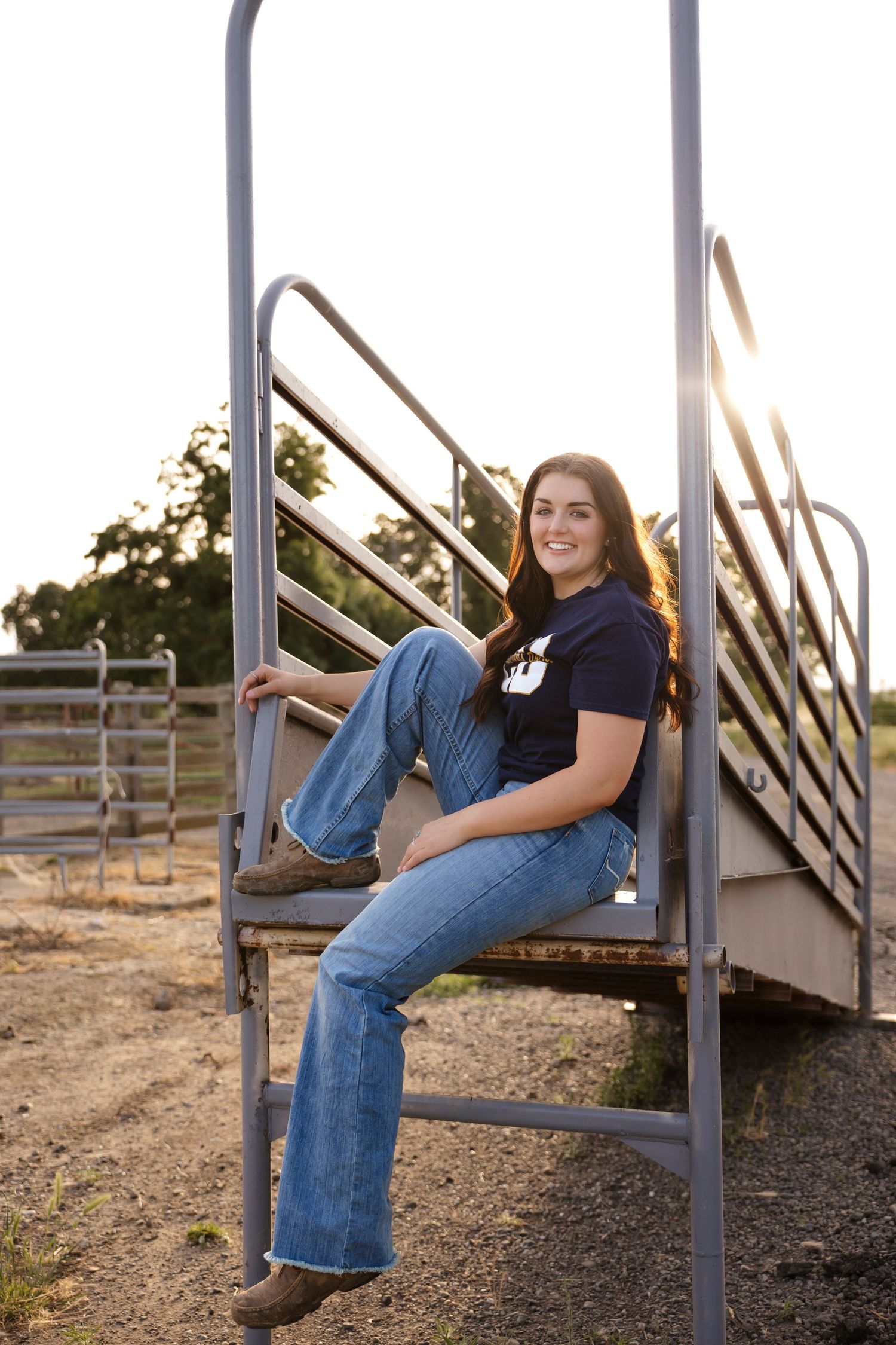Person in denim sits casually on metal stairs outdoors at dusk.