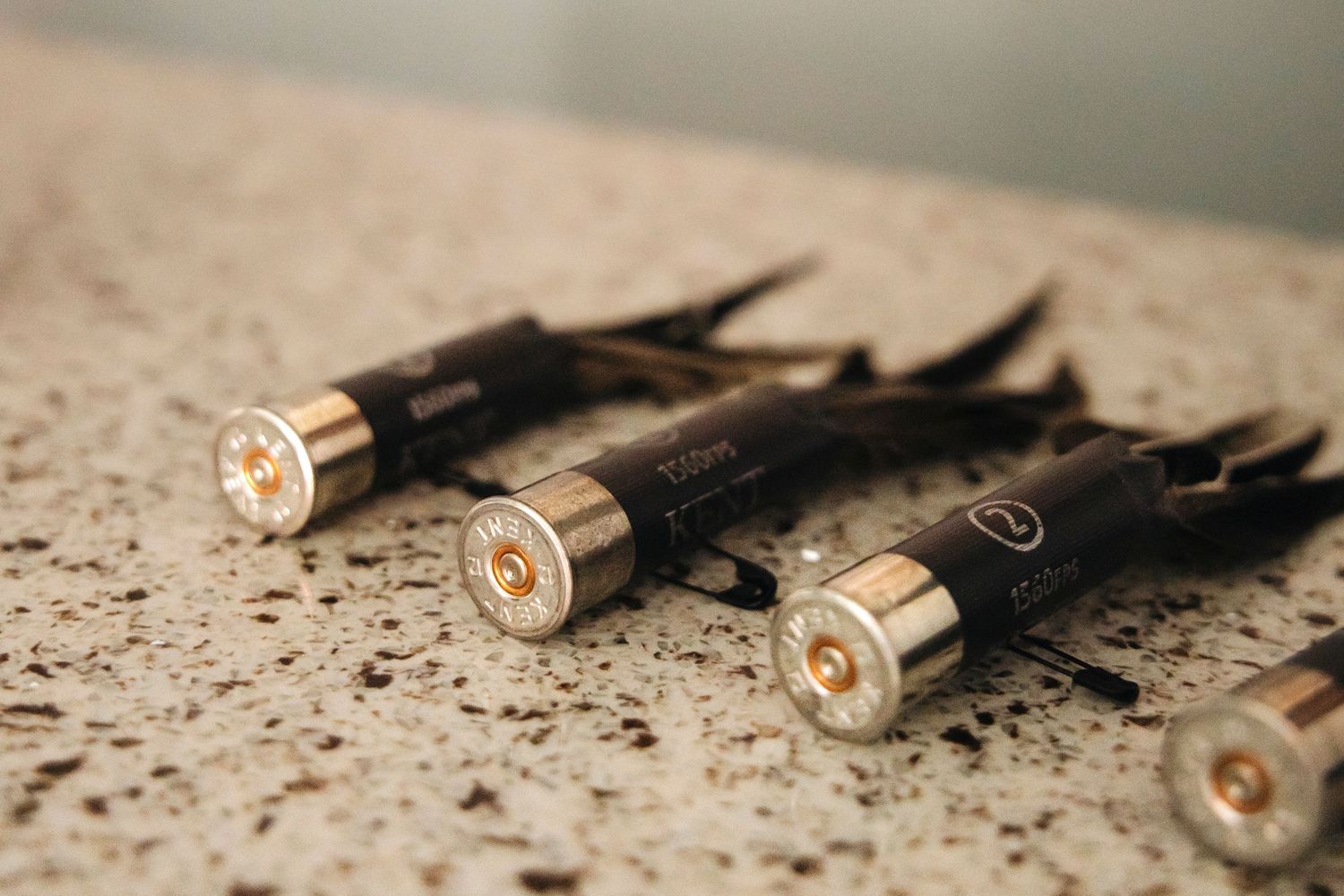Bullet shell casings and black objects arranged on a textured surface in a dramatic composition.