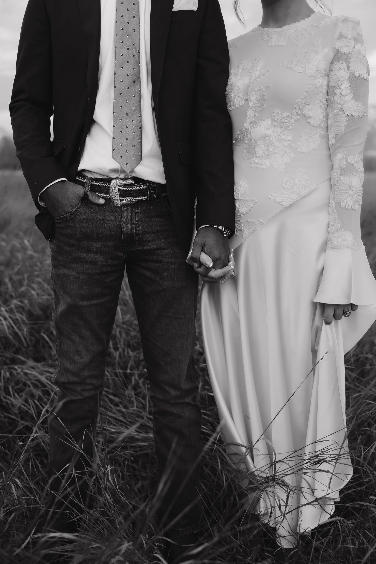 Black and white photo showing wedding attire details with denim jeans and white dress.