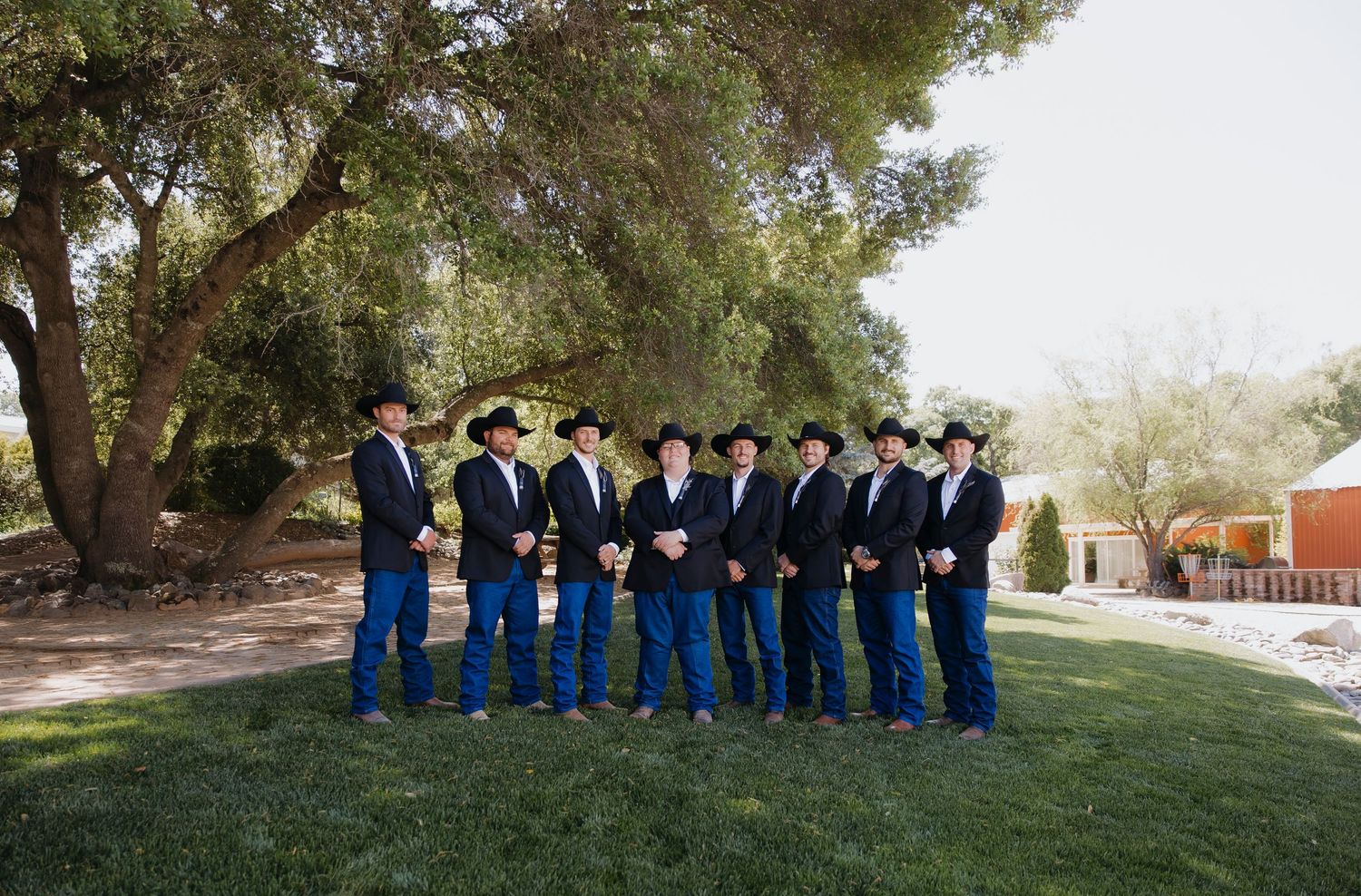 Group photo of people in blue attire standing in a line outdoors under trees.