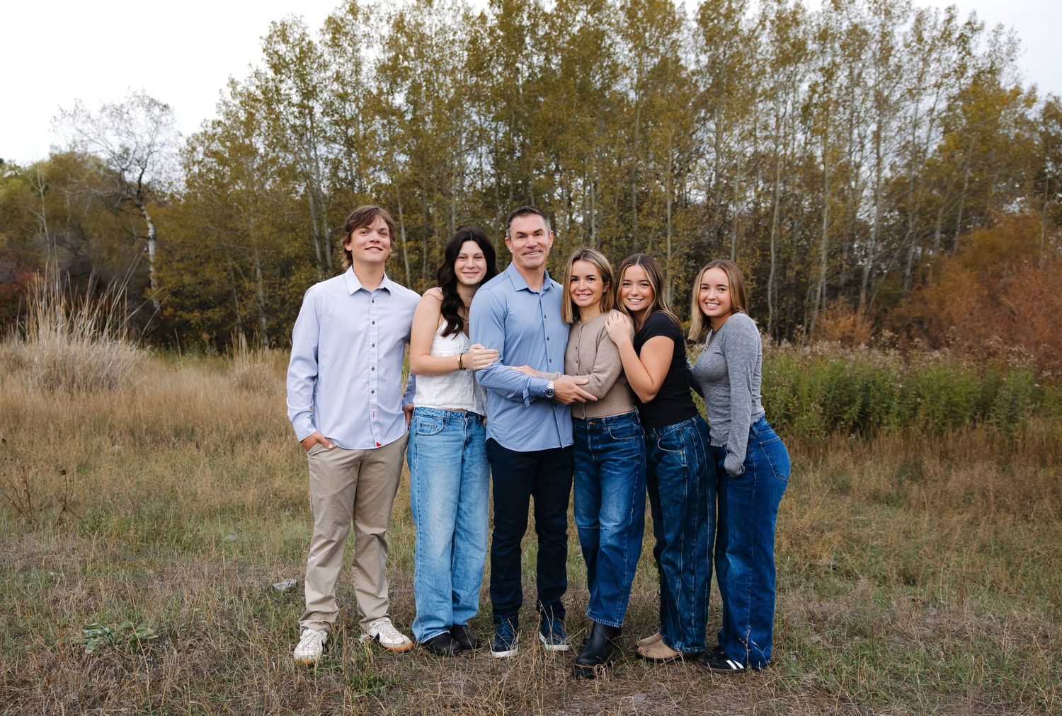 Group portrait lineup against autumn trees and natural landscape.