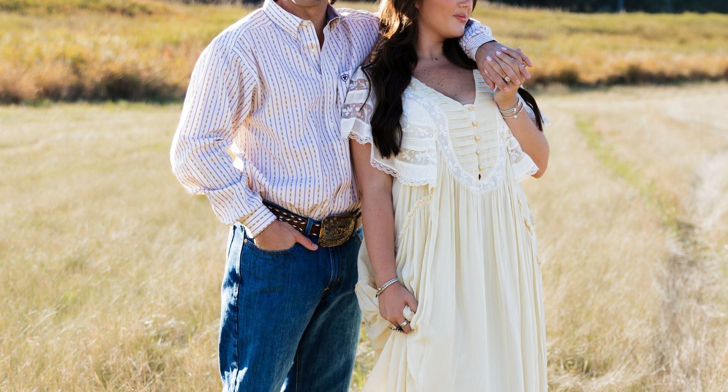 Couple walking hand in hand through a sun-lit meadow in autumn.