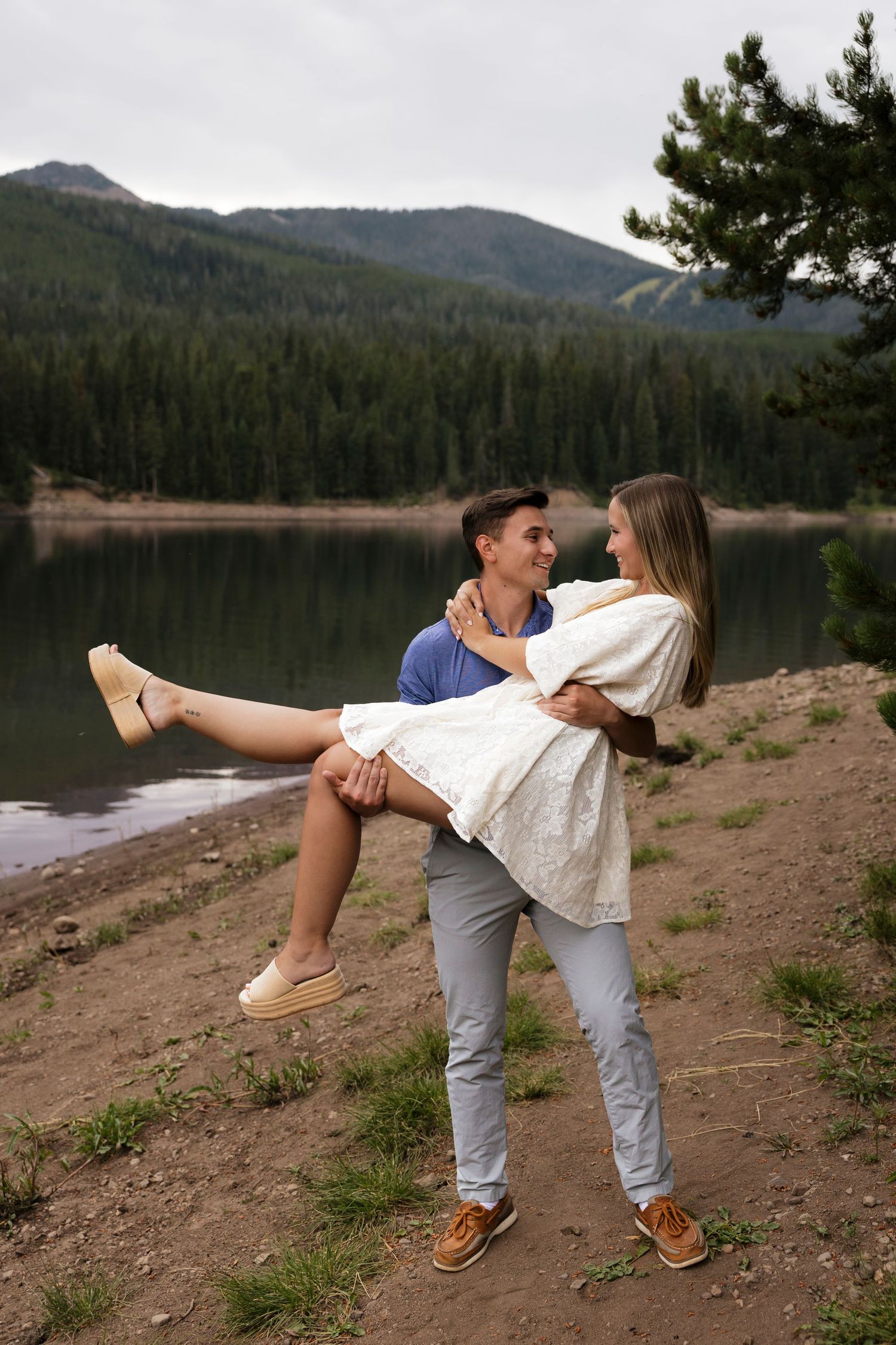 Couple sharing playful moments by a scenic mountain lake.