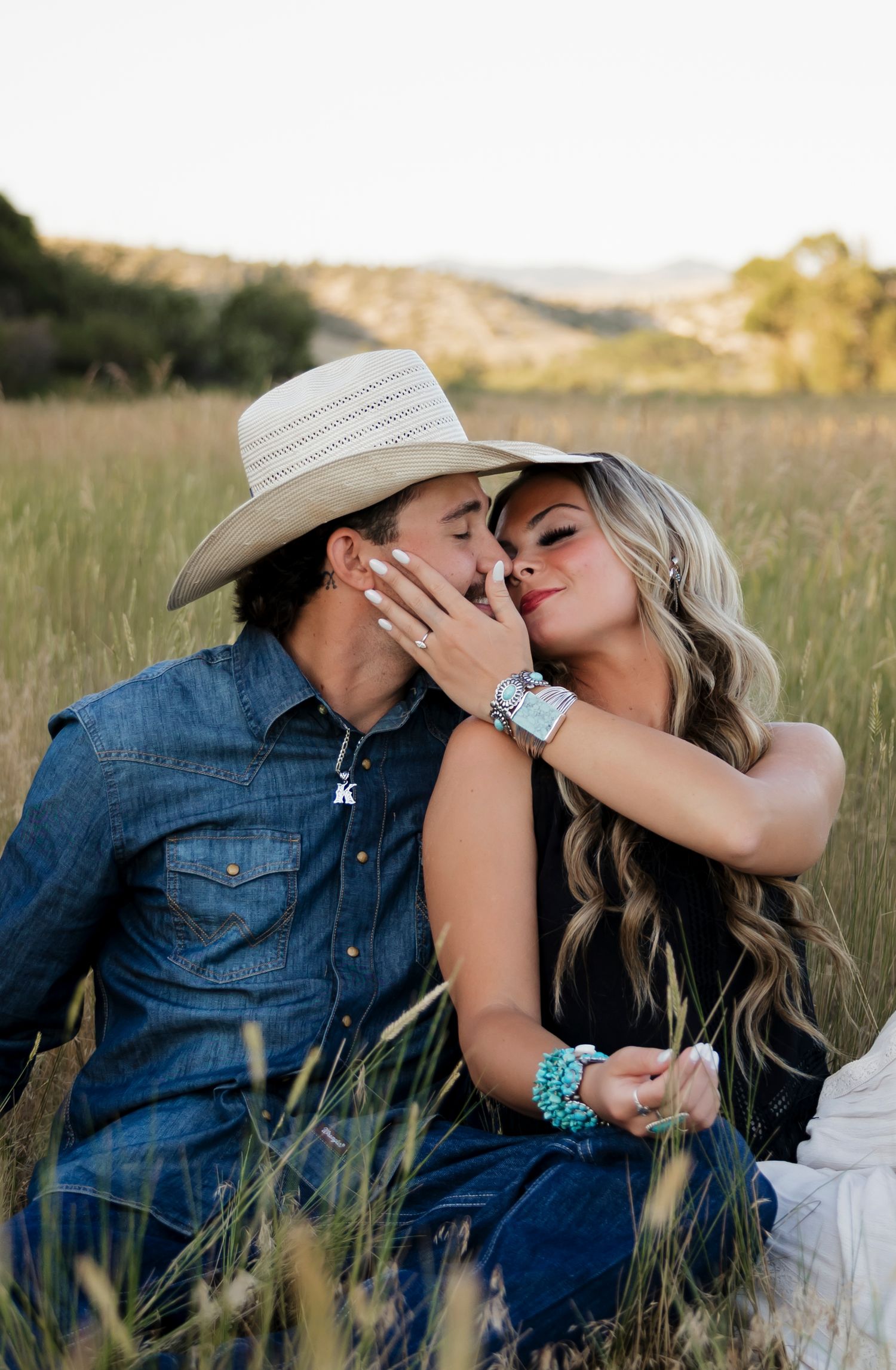 Intimate moments shared in tall grass during golden hour photoshoot.