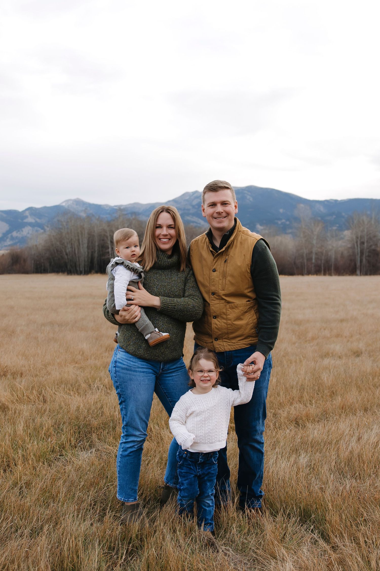 Family playing together in a golden autumn field with mountains in the background.