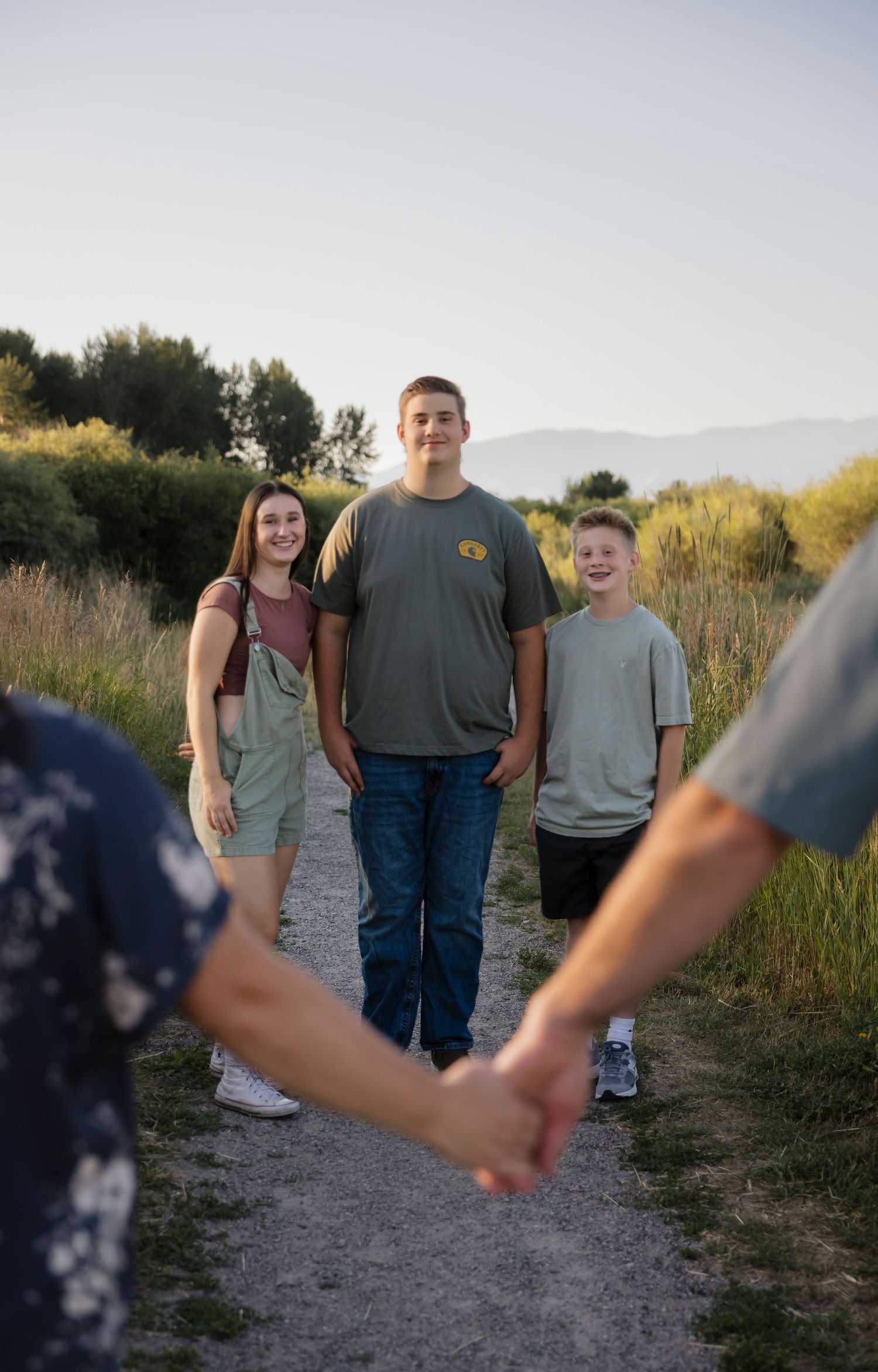Family photo session on a nature trail with mountains and greenery in background.