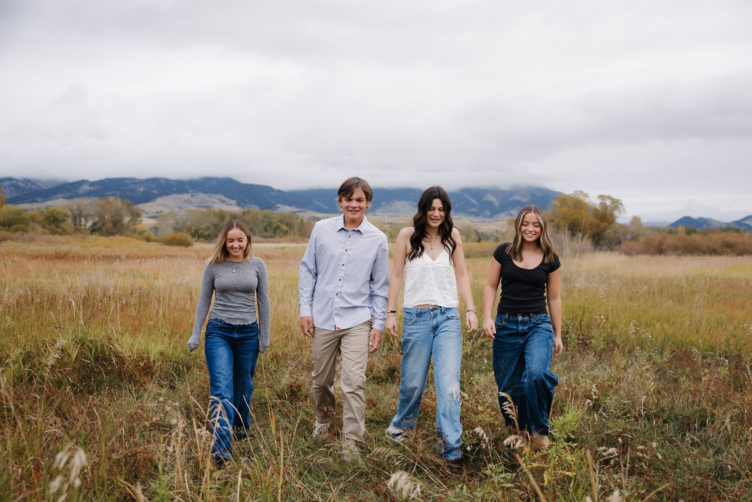 Casual outdoor family photo session in an open field with mountain backdrop.