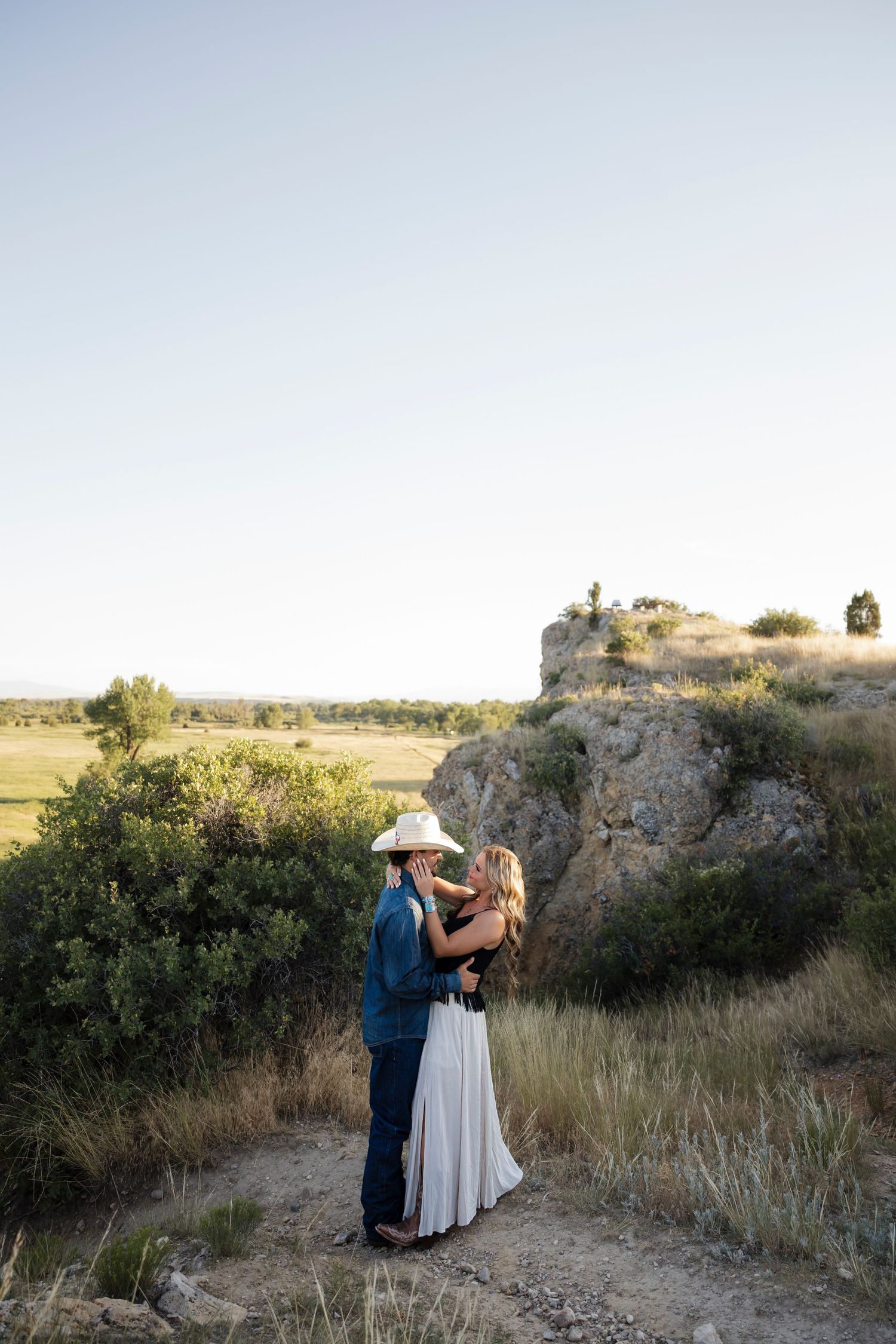 A couple embraces on rocky terrain during golden hour.