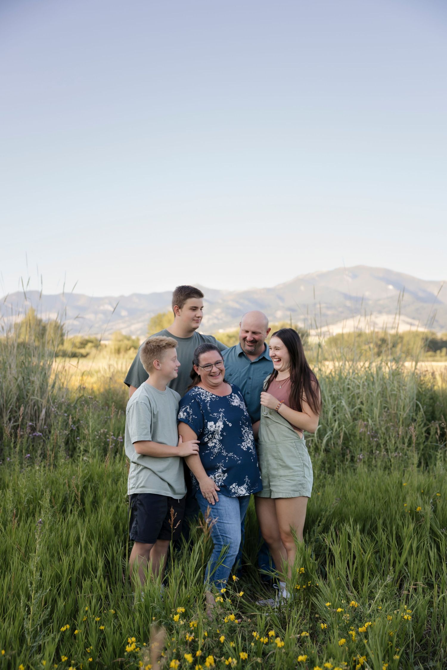 Group photo session in a wildflower meadow with mountains visible in the distance.