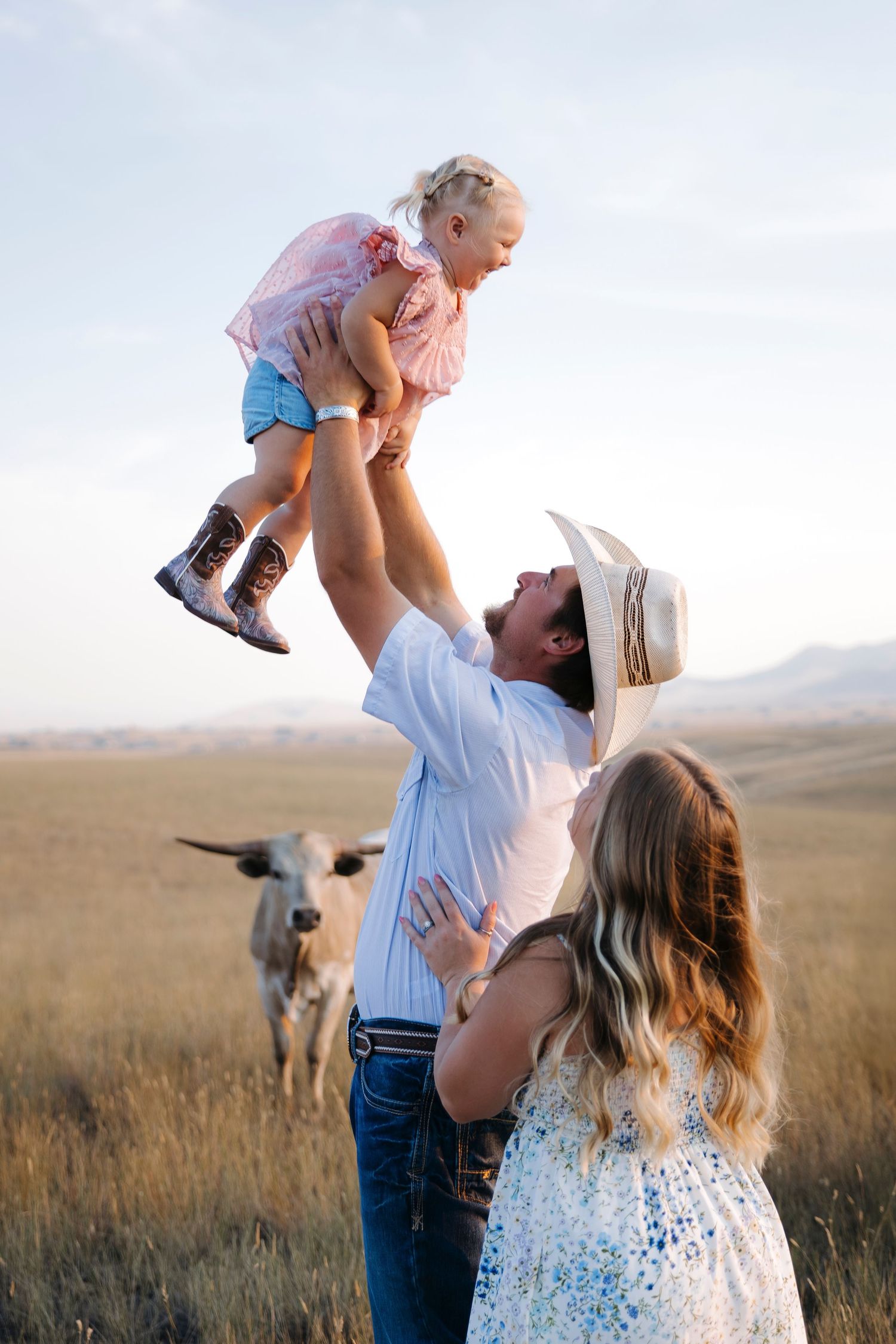 Playful family moment lifting child in air against scenic mountain backdrop.