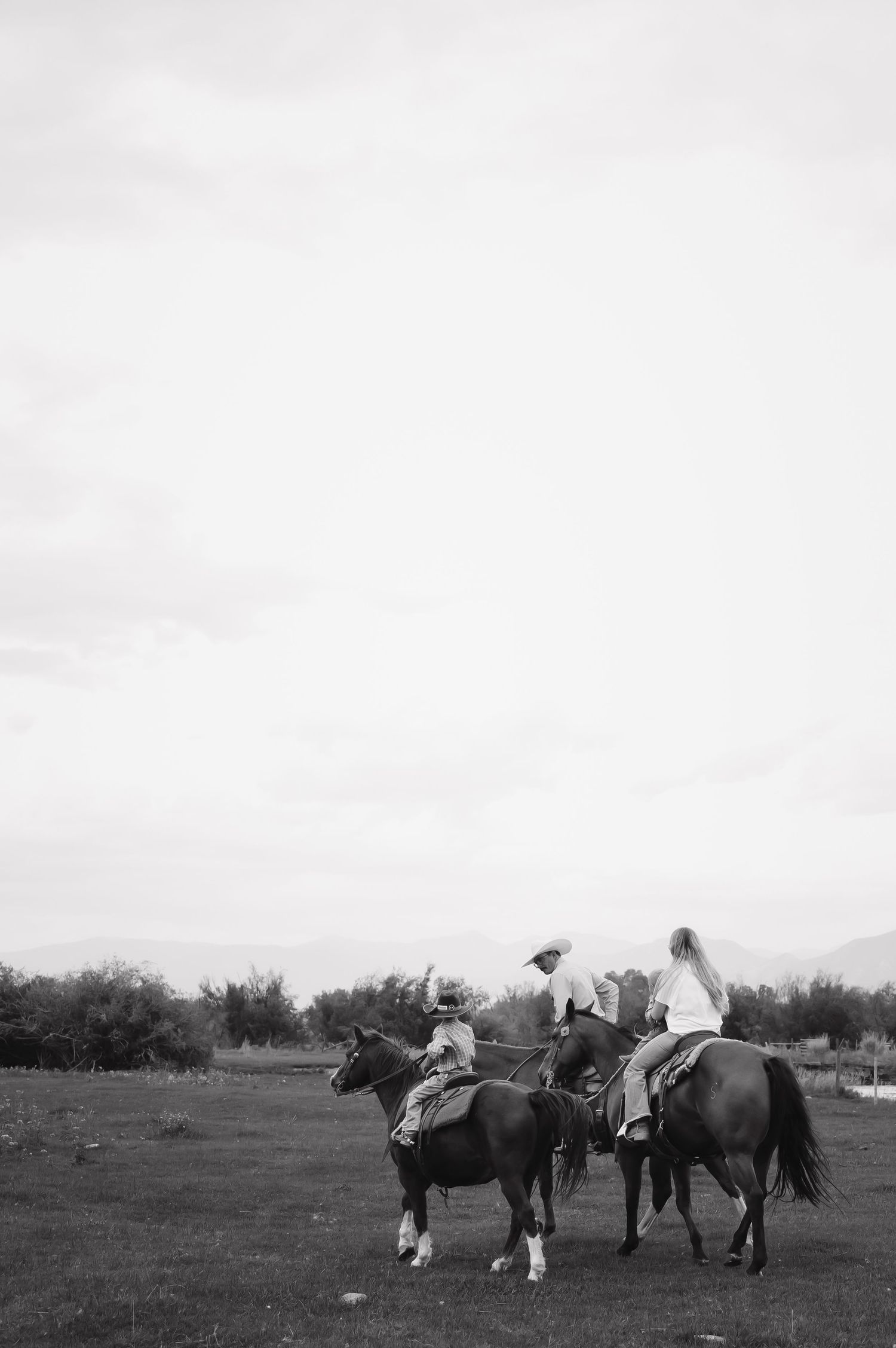 Vintage black and white photograph showing horses and riders gathered in a field.
