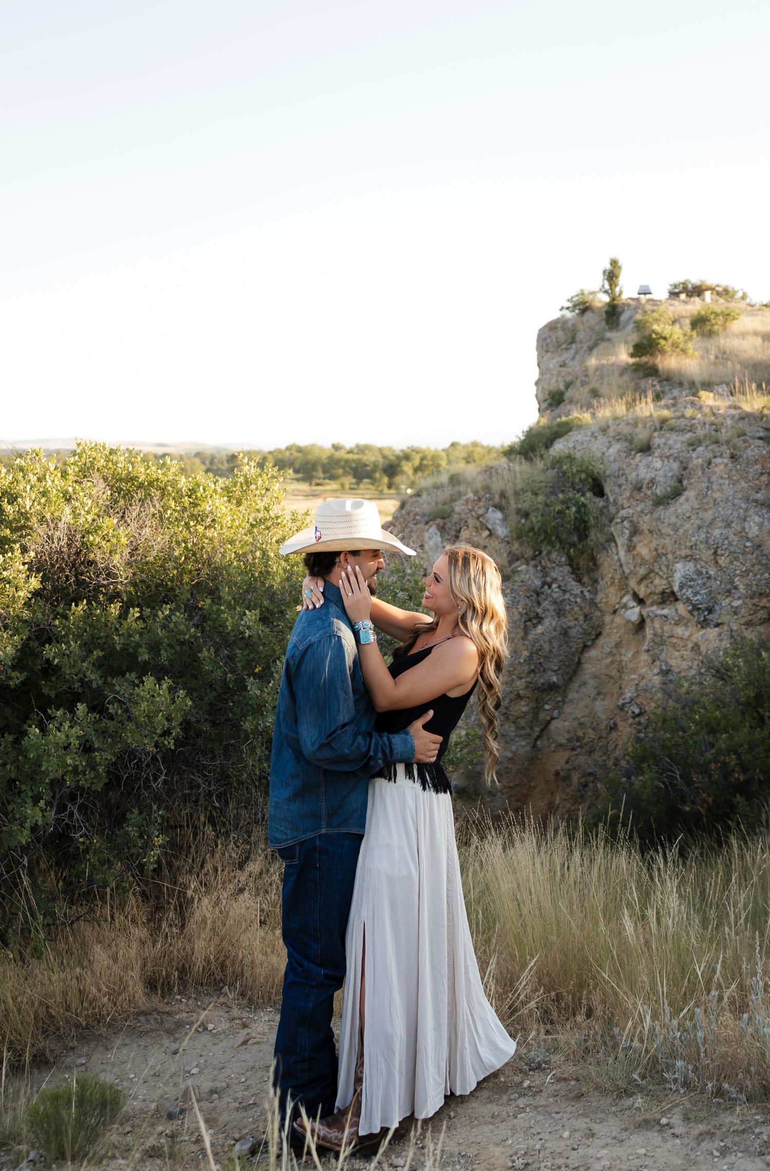 Romantic moment captured against rocky desert backdrop at golden hour.