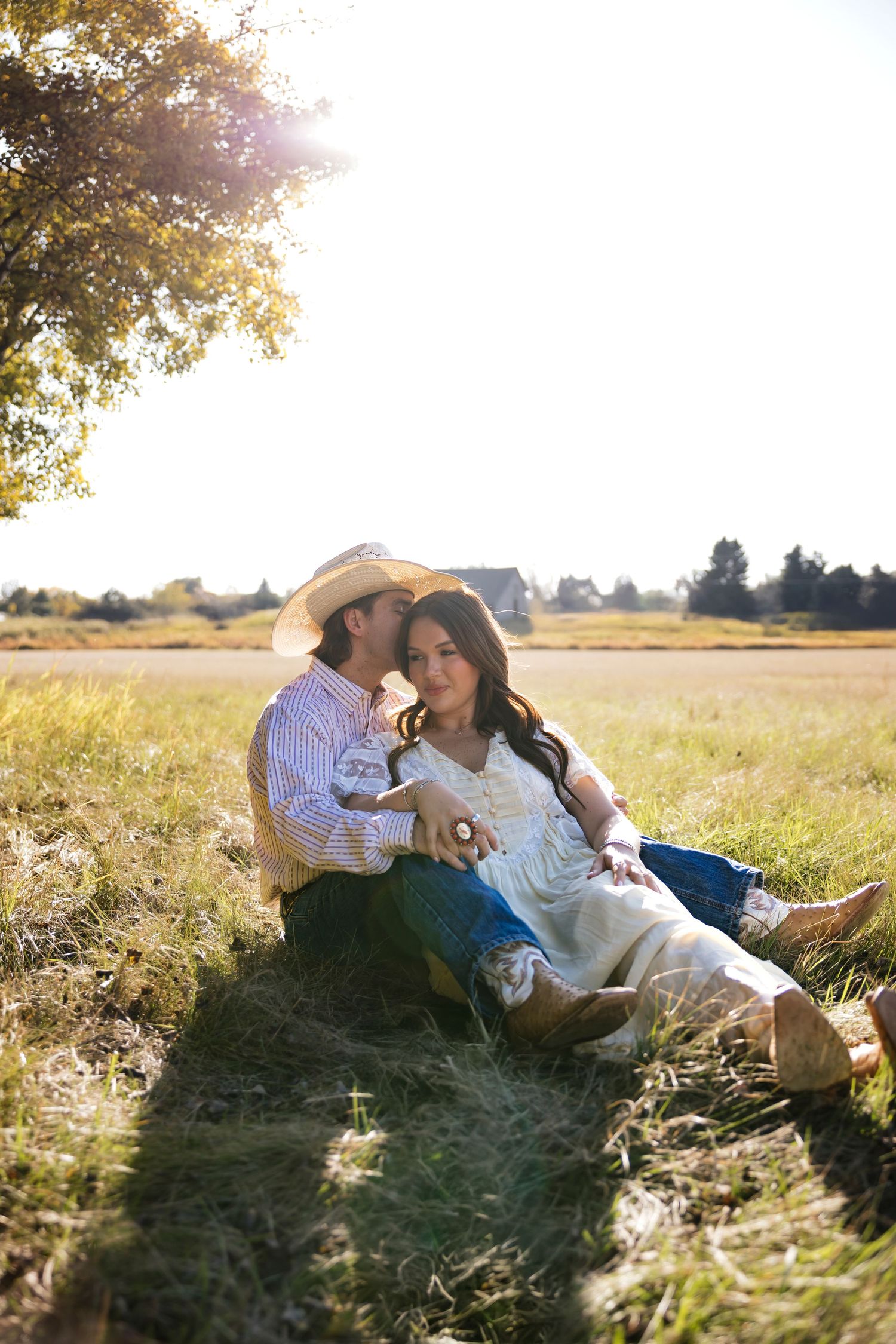 Couple relaxes together in sunlit meadow during romantic countryside photoshoot.