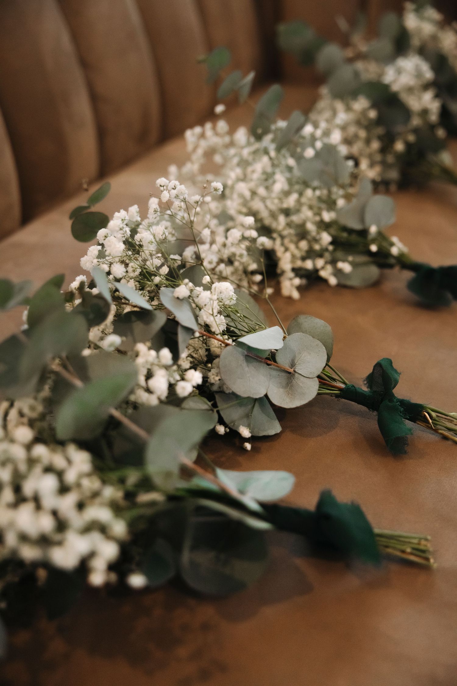Delicate white baby's breath and eucalyptus floral arrangement on wooden surface.