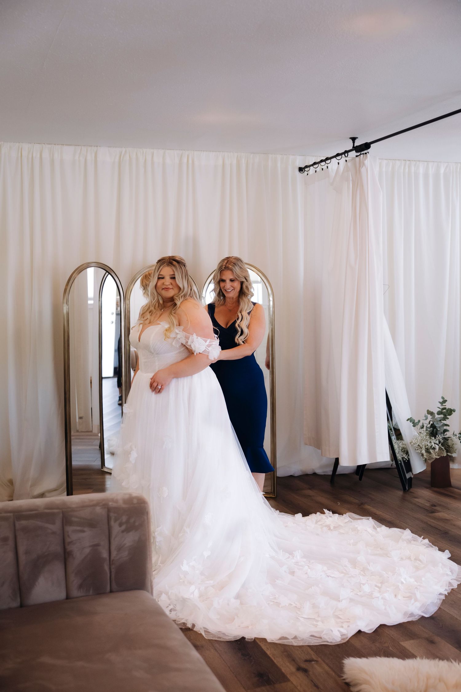 Elegant white wedding gown with long train displayed in a bright room.