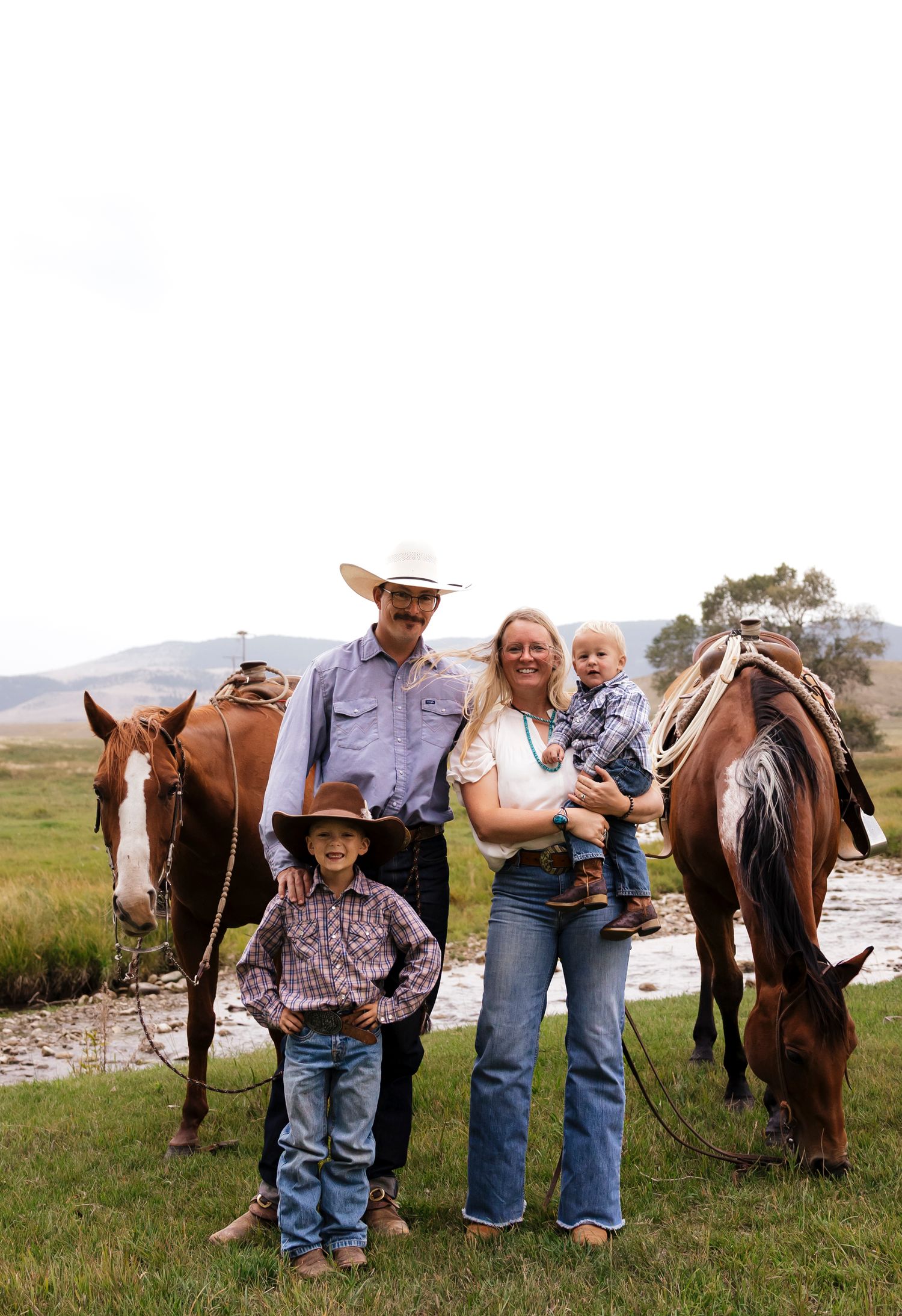 Group gathering with horses in a grassy field on an overcast day.