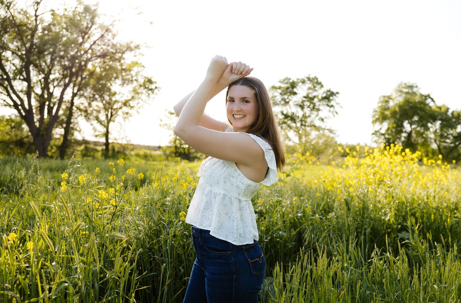 Golden sunlight illuminates a field of tall grass and wildflowers during sunset.
