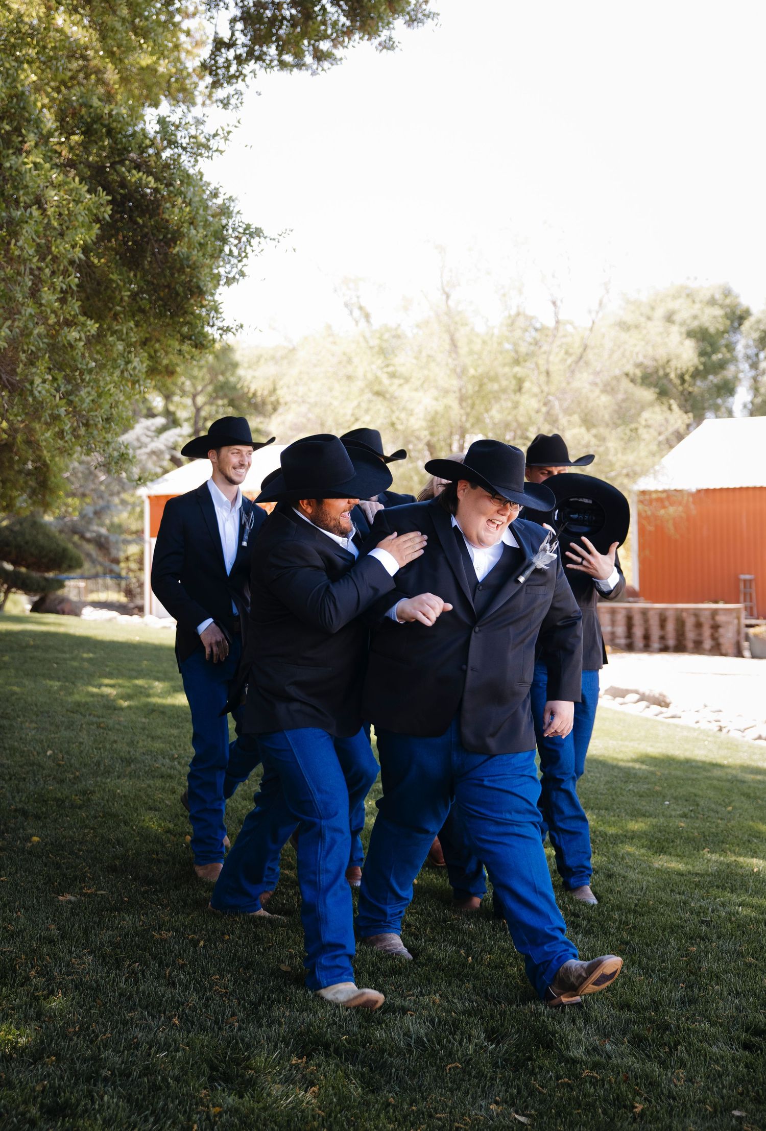 People in blue clothing and black hats gathered on a grassy lawn.