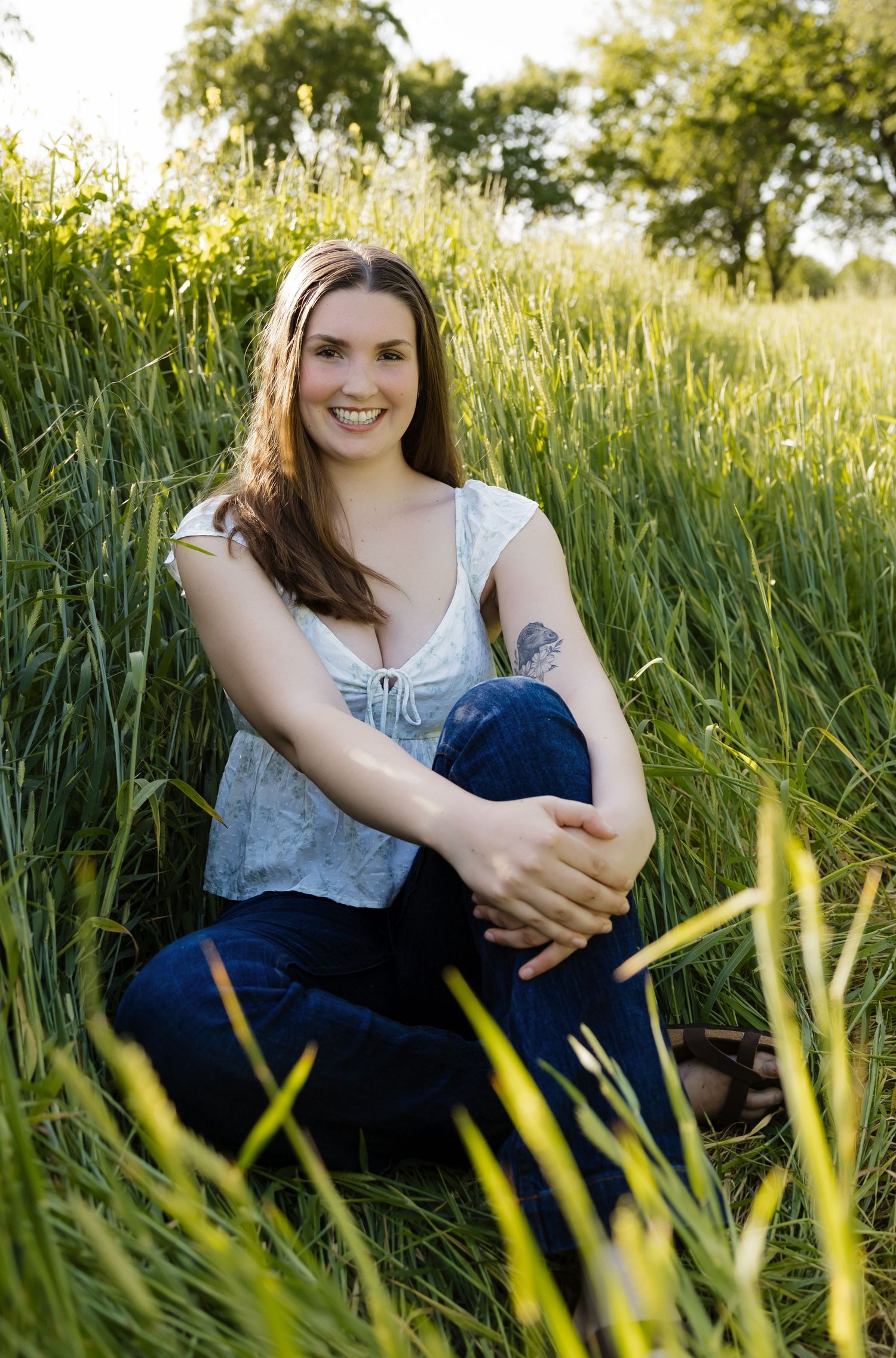 A casual outdoor portrait session in tall grass with natural evening lighting.