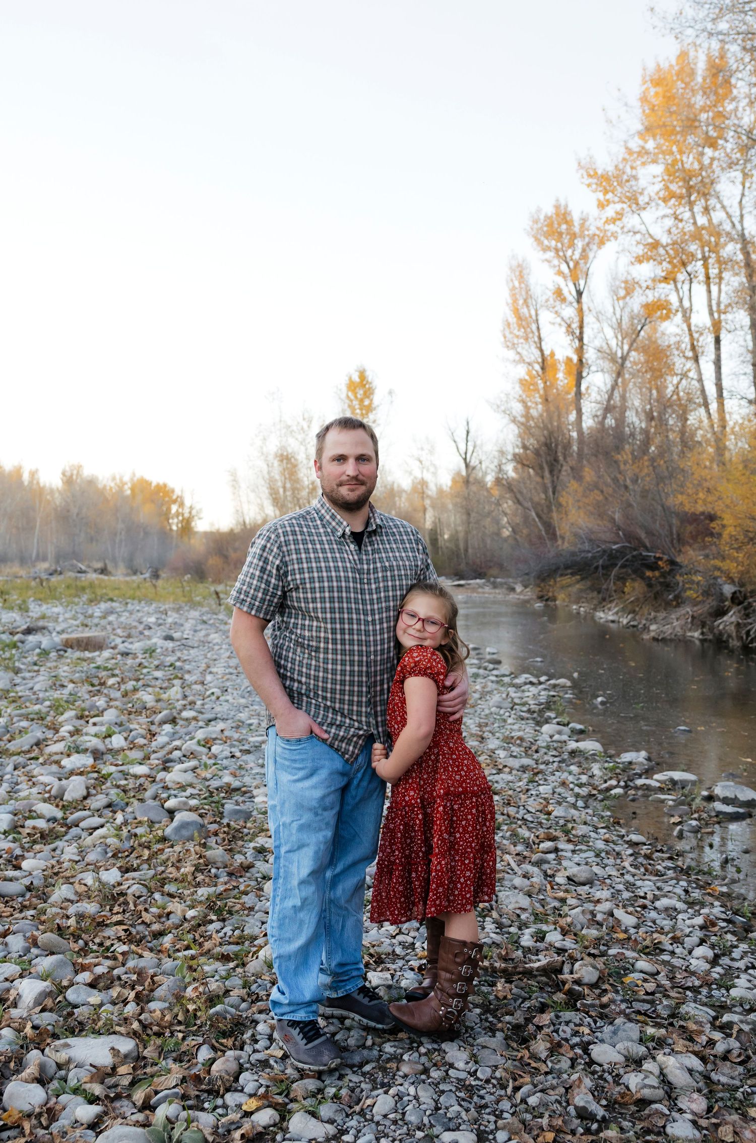 Family spending time together on a rocky riverbank during fall season.