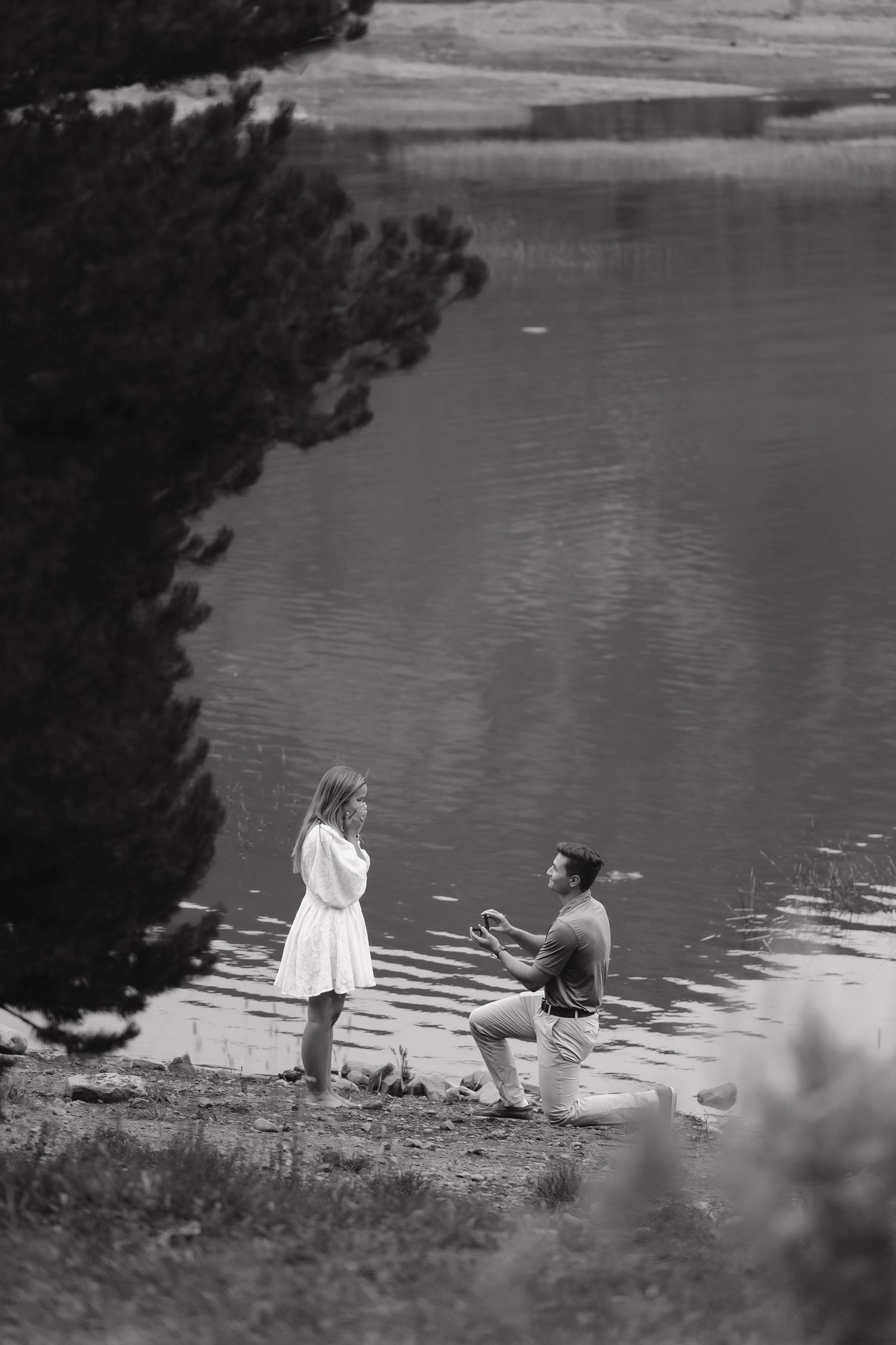 A black and white photo of people relaxing by a serene lakeside.