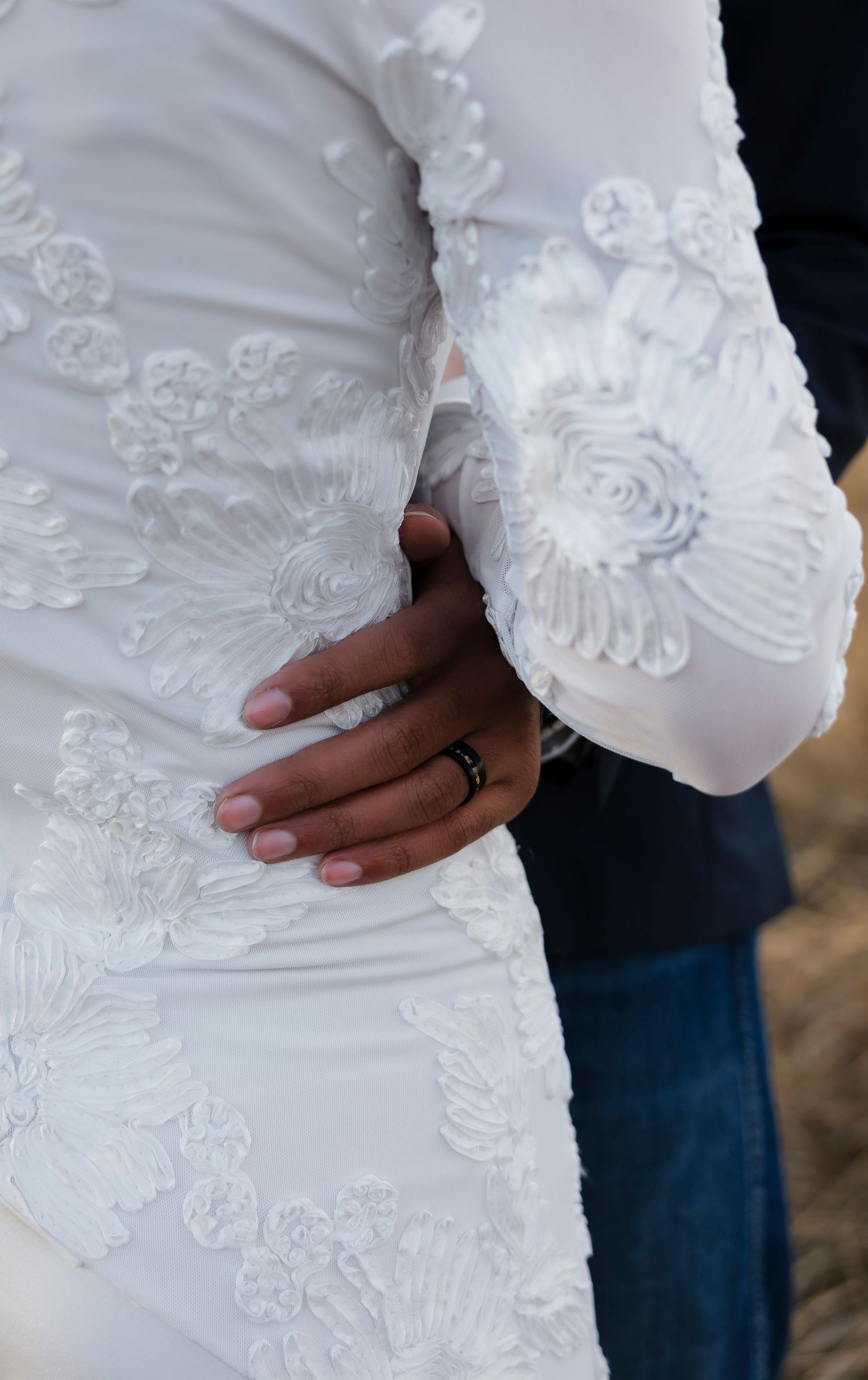 Close-up details of intricate white lace and floral patterns on a wedding dress.