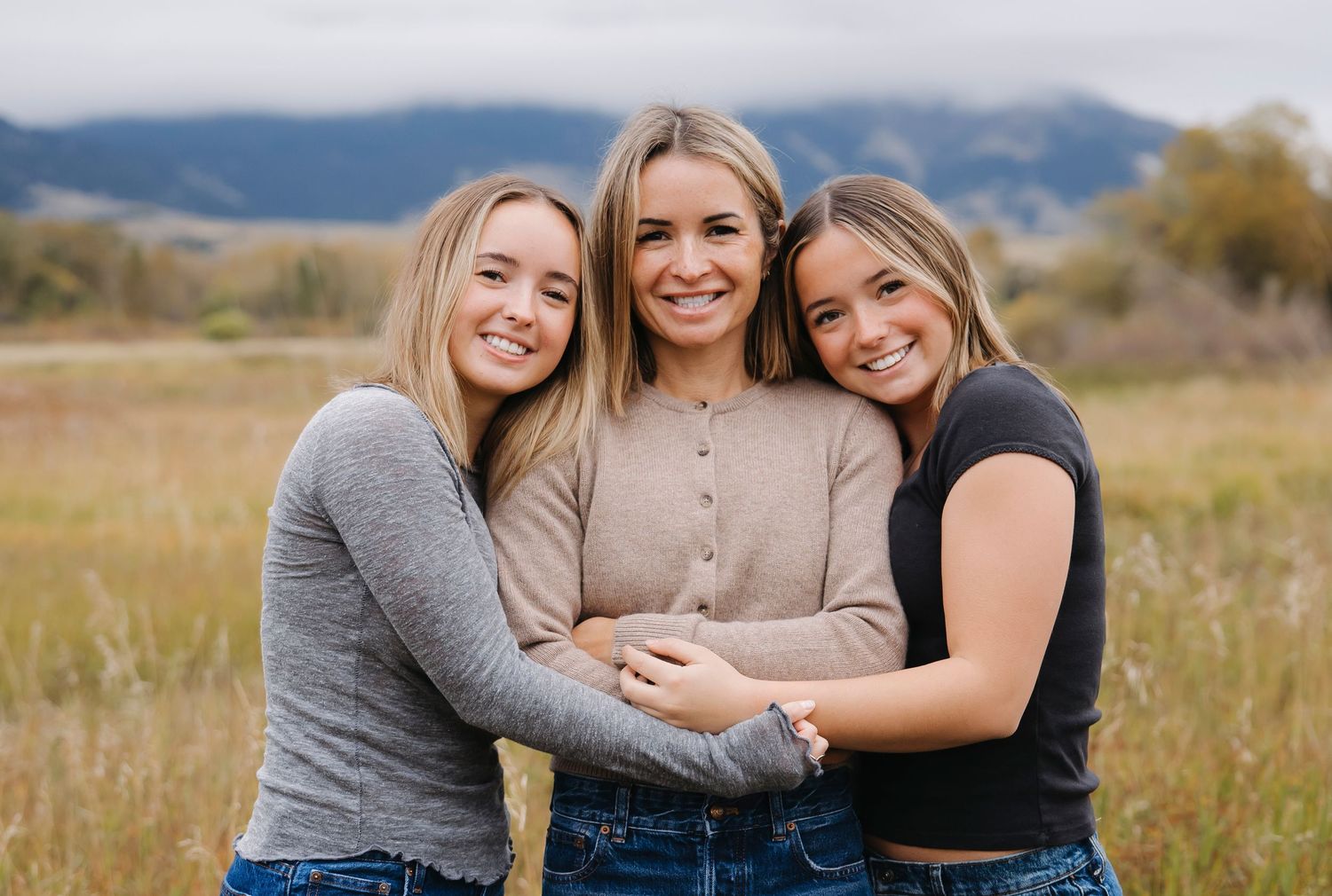 Close-up portrait of friends embracing and smiling in an autumn field.