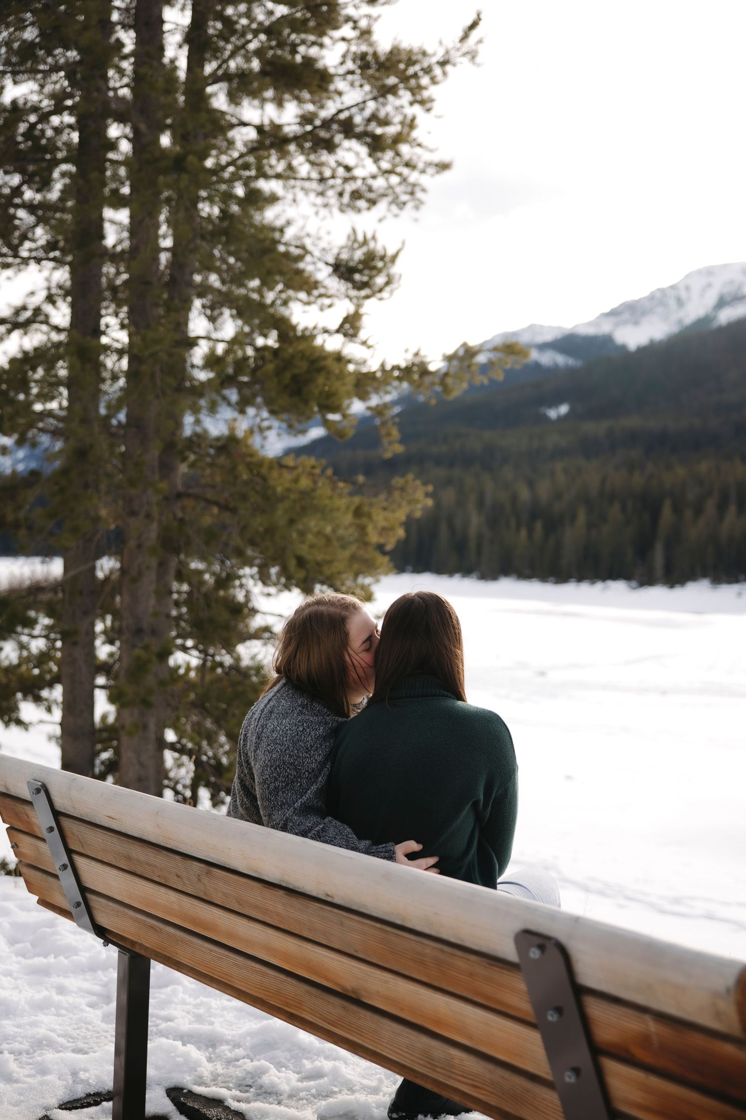 LGBTQ couple sitting on the bench surrounded by the mountains