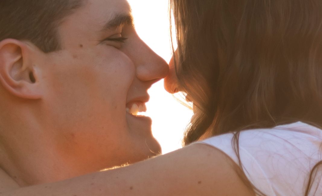 A romantic couple sharing intimate close-up moments in golden sunlight.