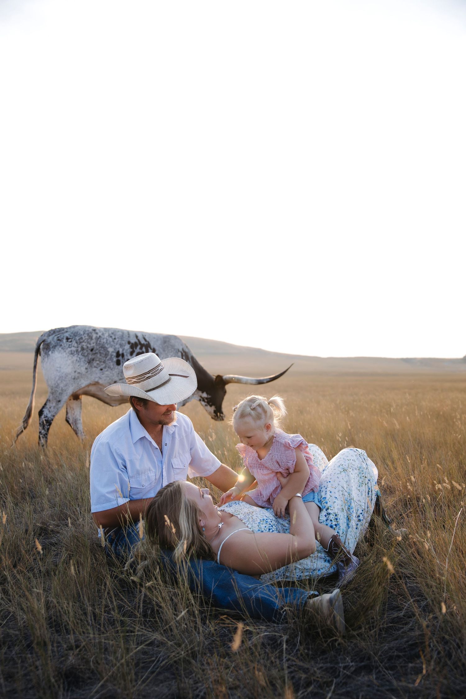 Candid family portrait session in a rustic field with mountains on the horizon.