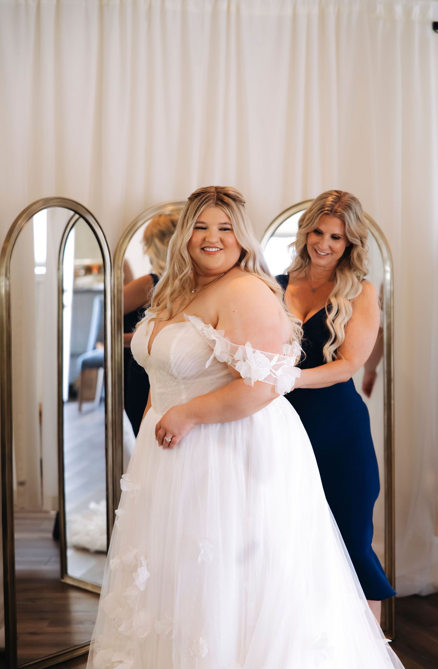 Wedding dress fitting scene with white gown and mirror reflections.