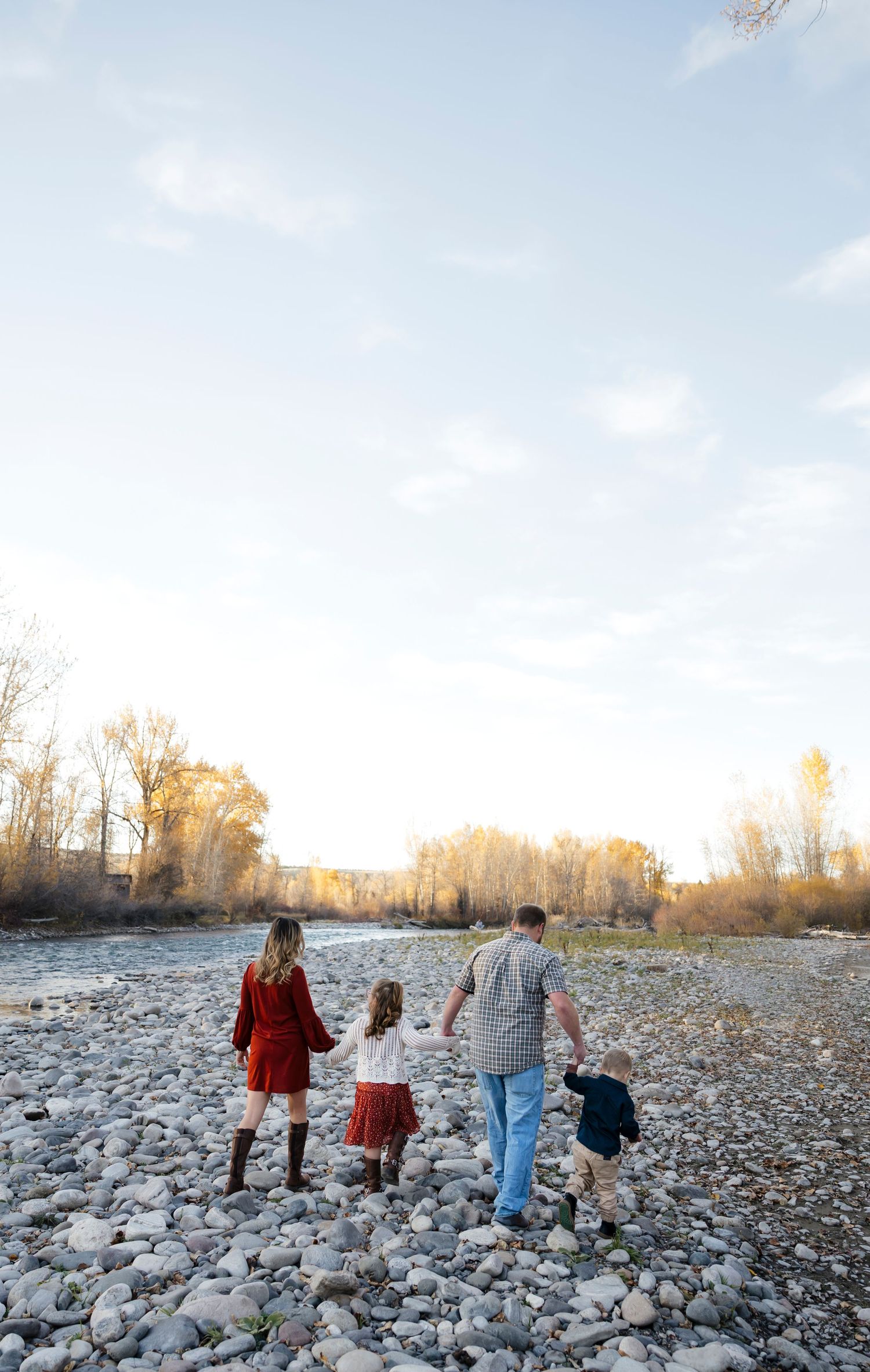 Group walking together on a rocky riverbed during golden hour with fall foliage.
