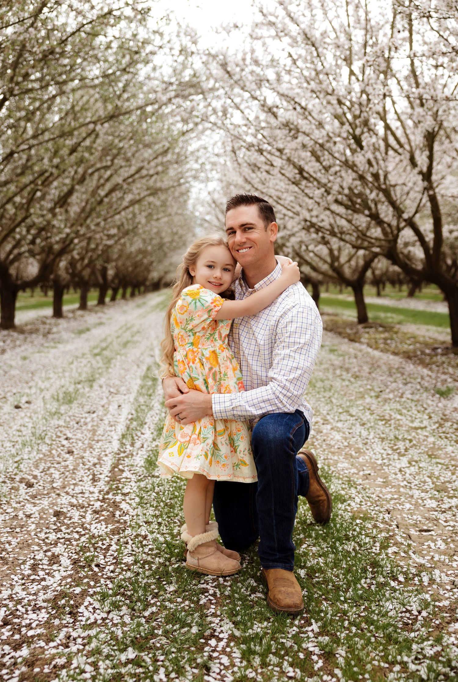 Sweet moment captured in orchard with white flower petals scattered on ground.